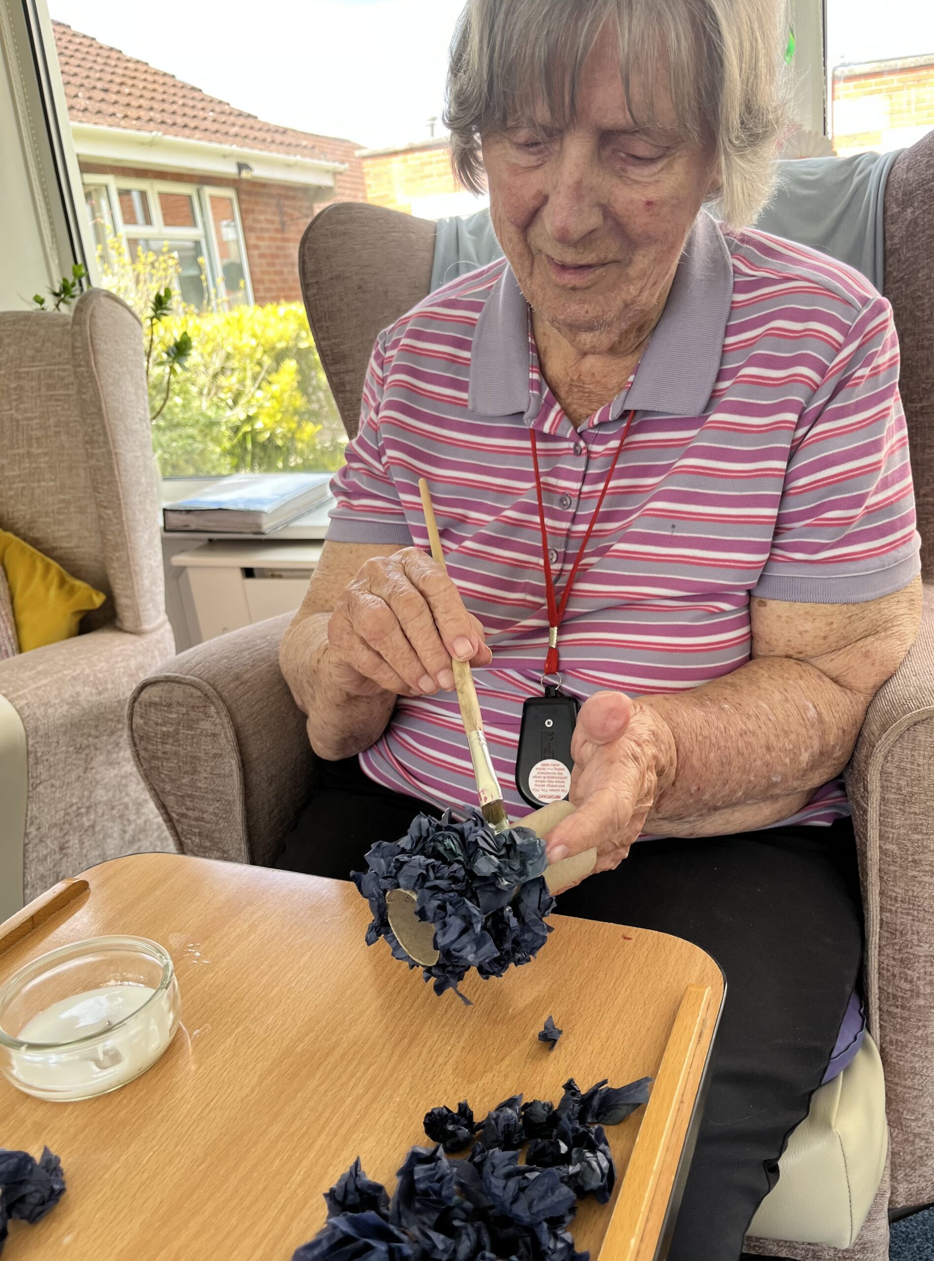 Barb being creative gluing the black tissue paper petals to a cardboard roll scaled