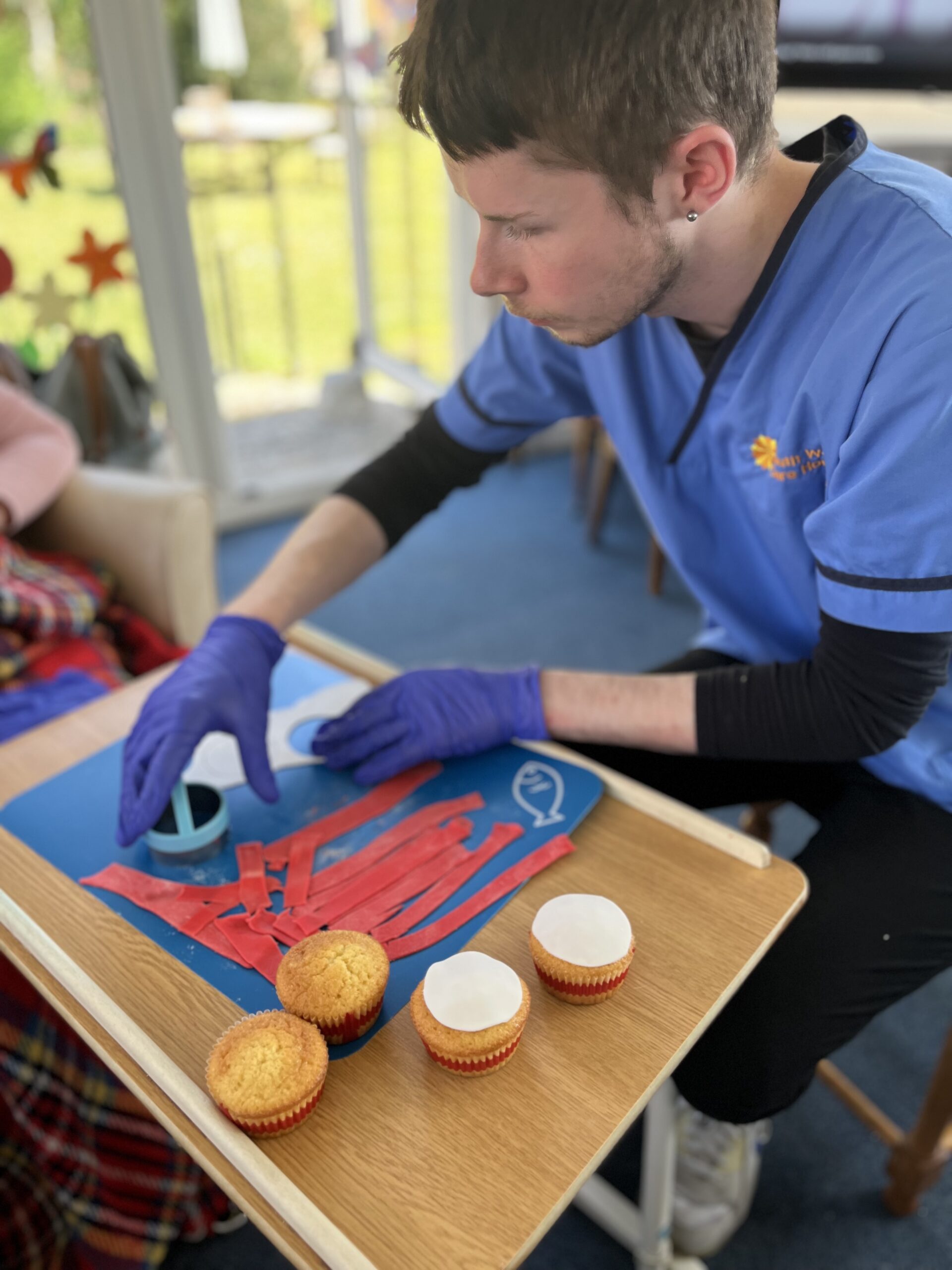 Carer Archie helping cut out white icing circles Carer Archie helping cut out white icing circles scaled