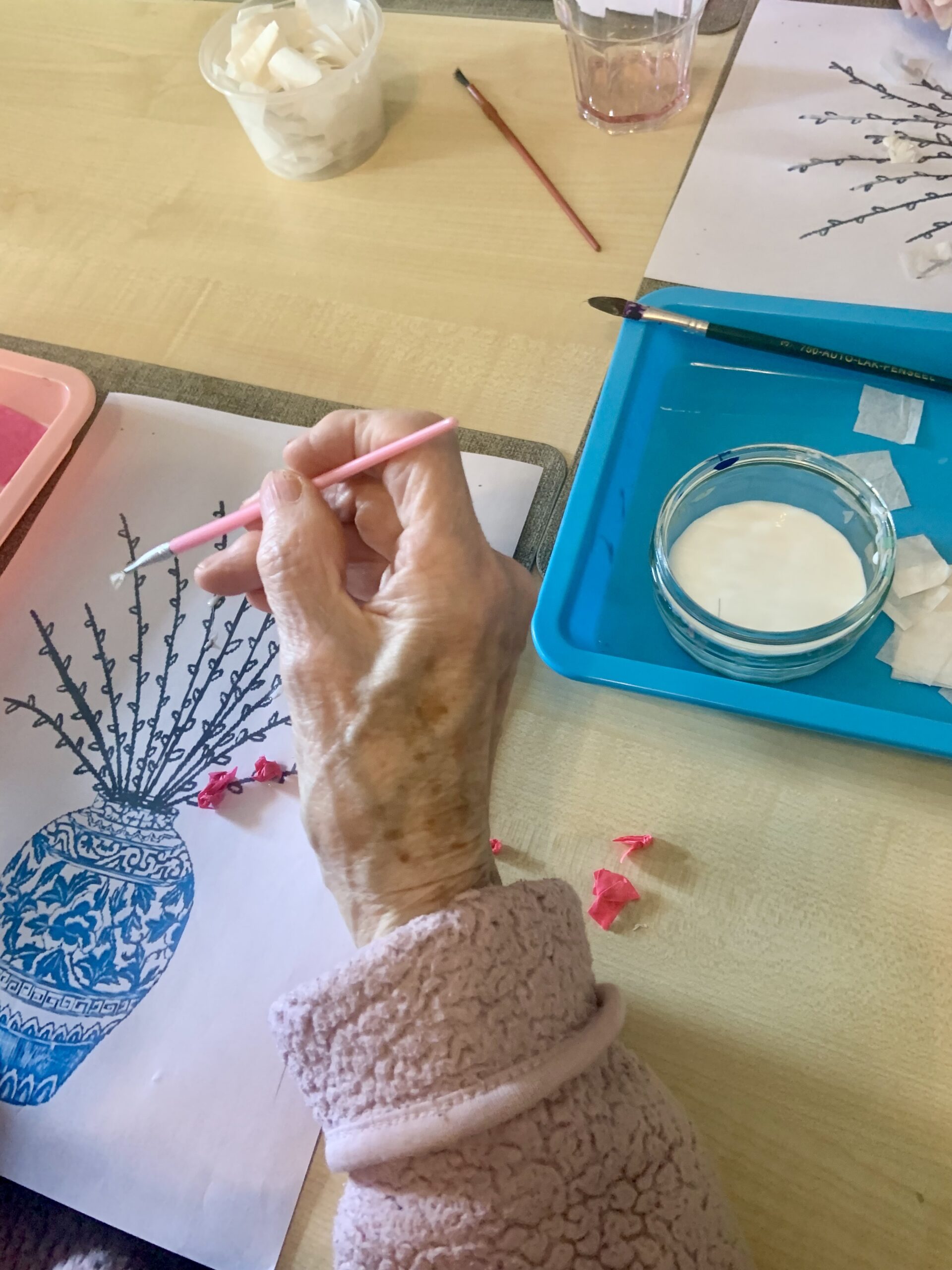Close up of a female resident placing glue on her picture with a fine brush scaled
