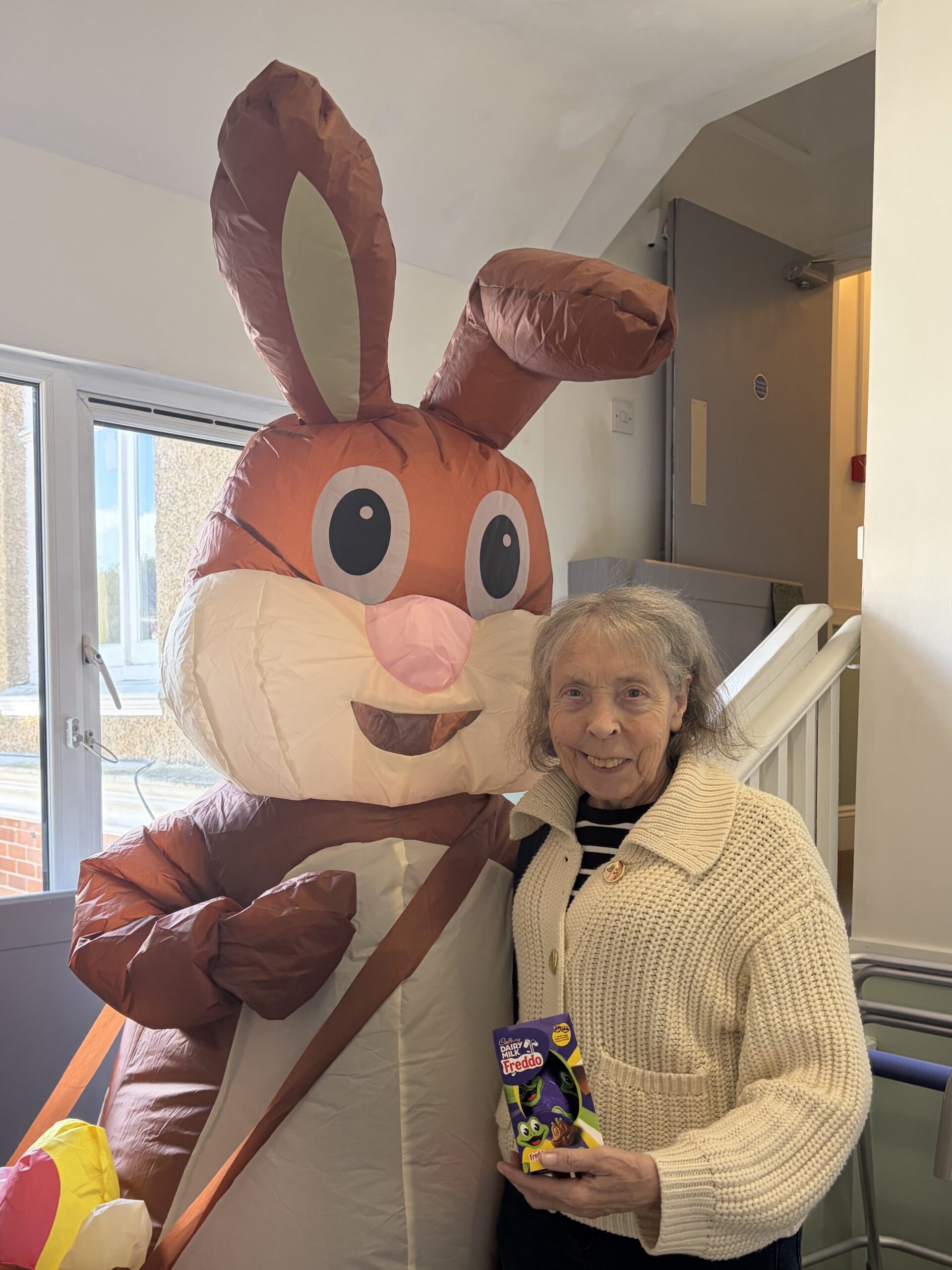 Easter bunny giving a chocolate egg to a female resident scaled