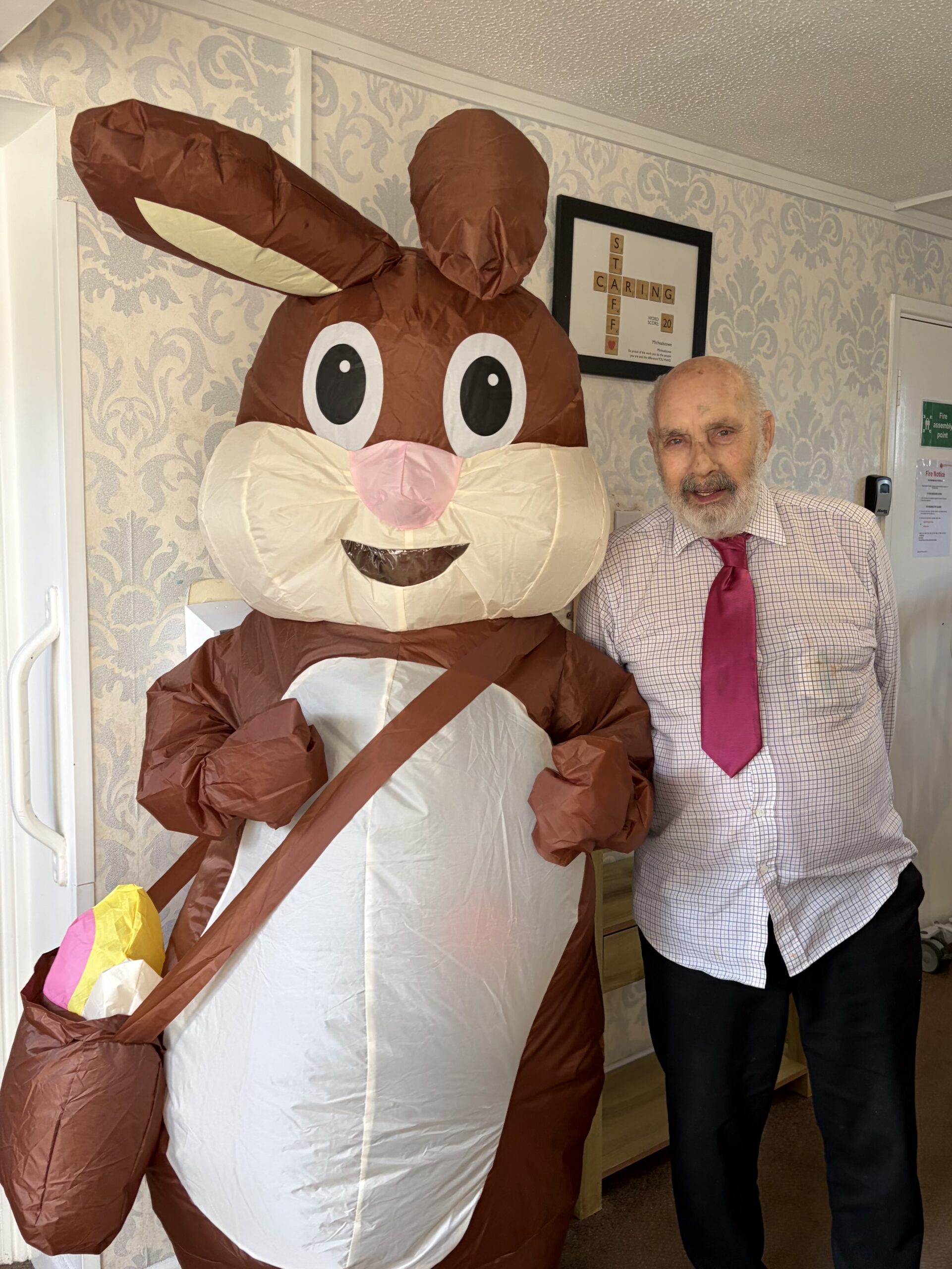 Easter bunny stood with a smiling male resident scaled