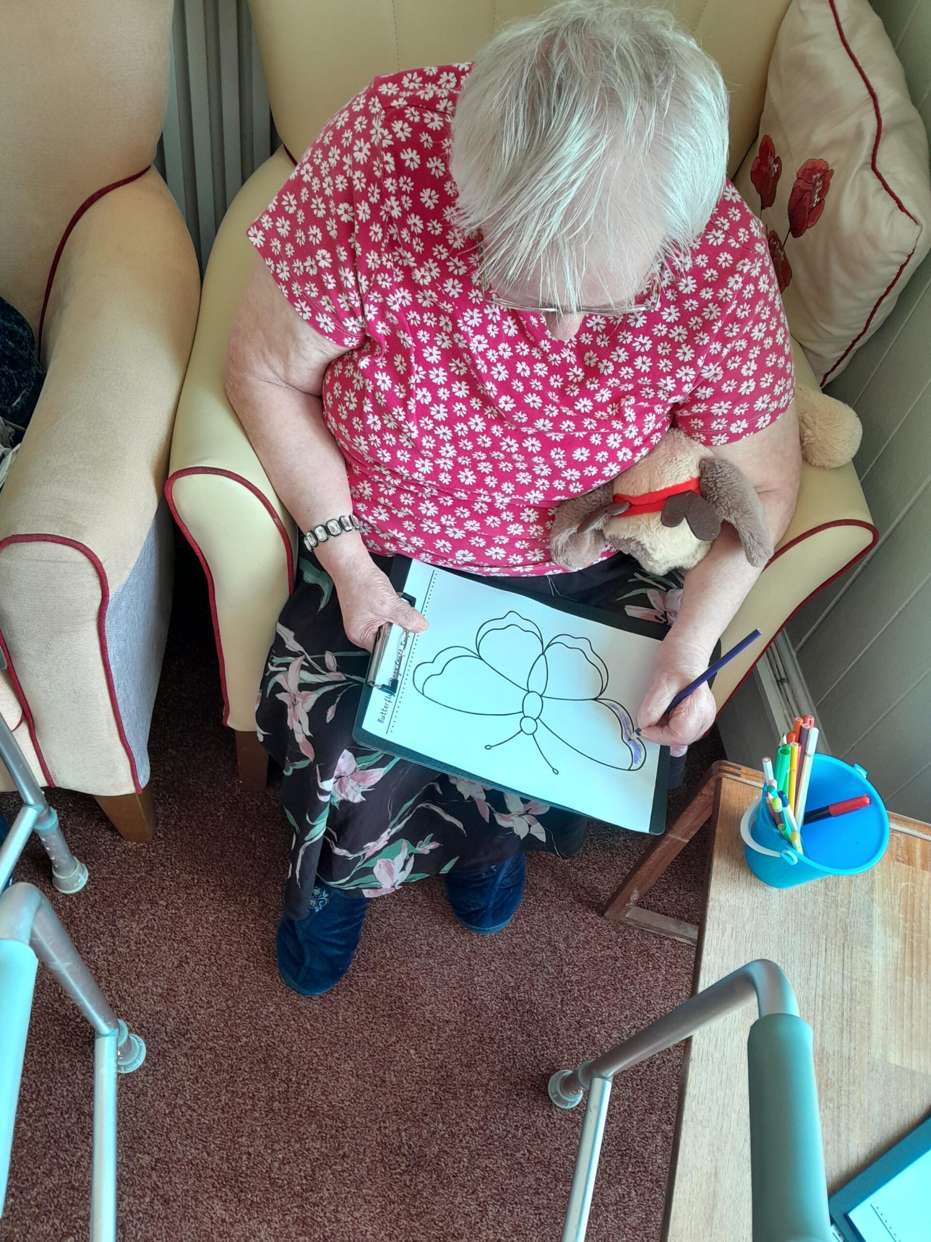 Female resident colouring in a butterfly with a purple colour pencil scaled