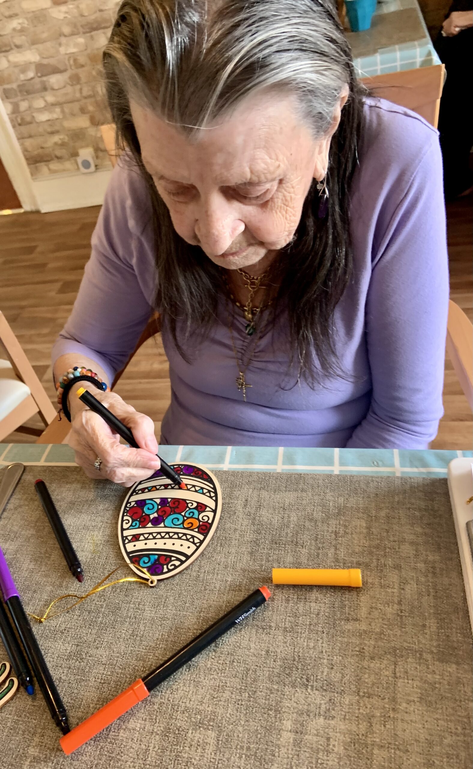 Female resident colouring in a paper Easter egg with felt tip pens scaled