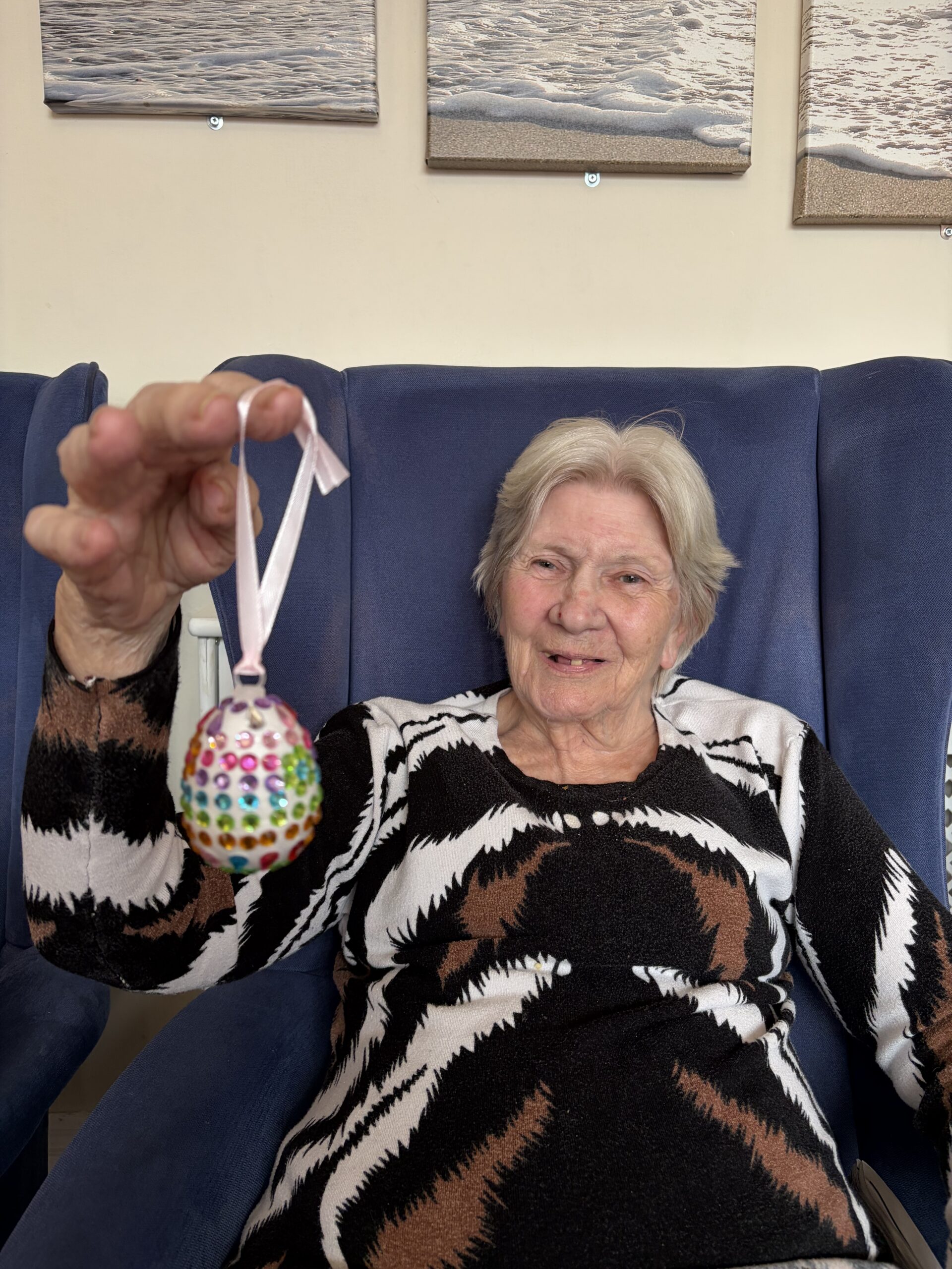 Female resident holding her decorated egg with different coloured sequins scaled
