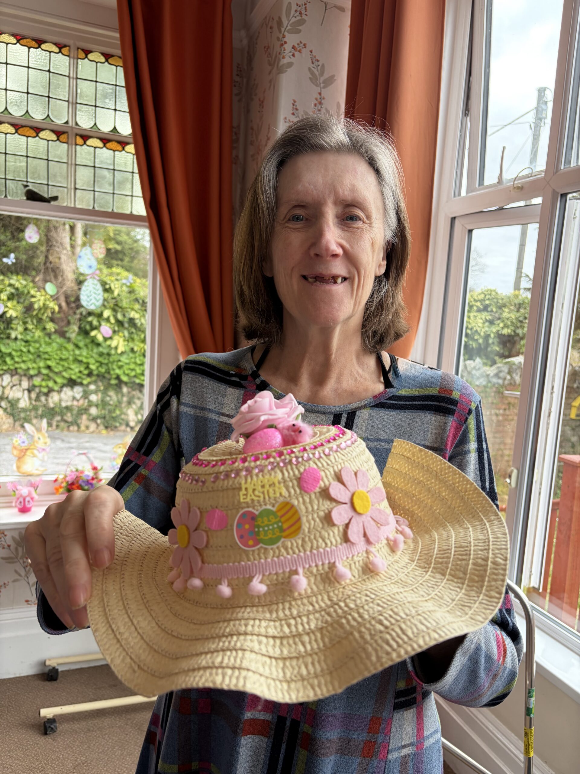 Female resident holding her finished decorated Easter bonnet scaled