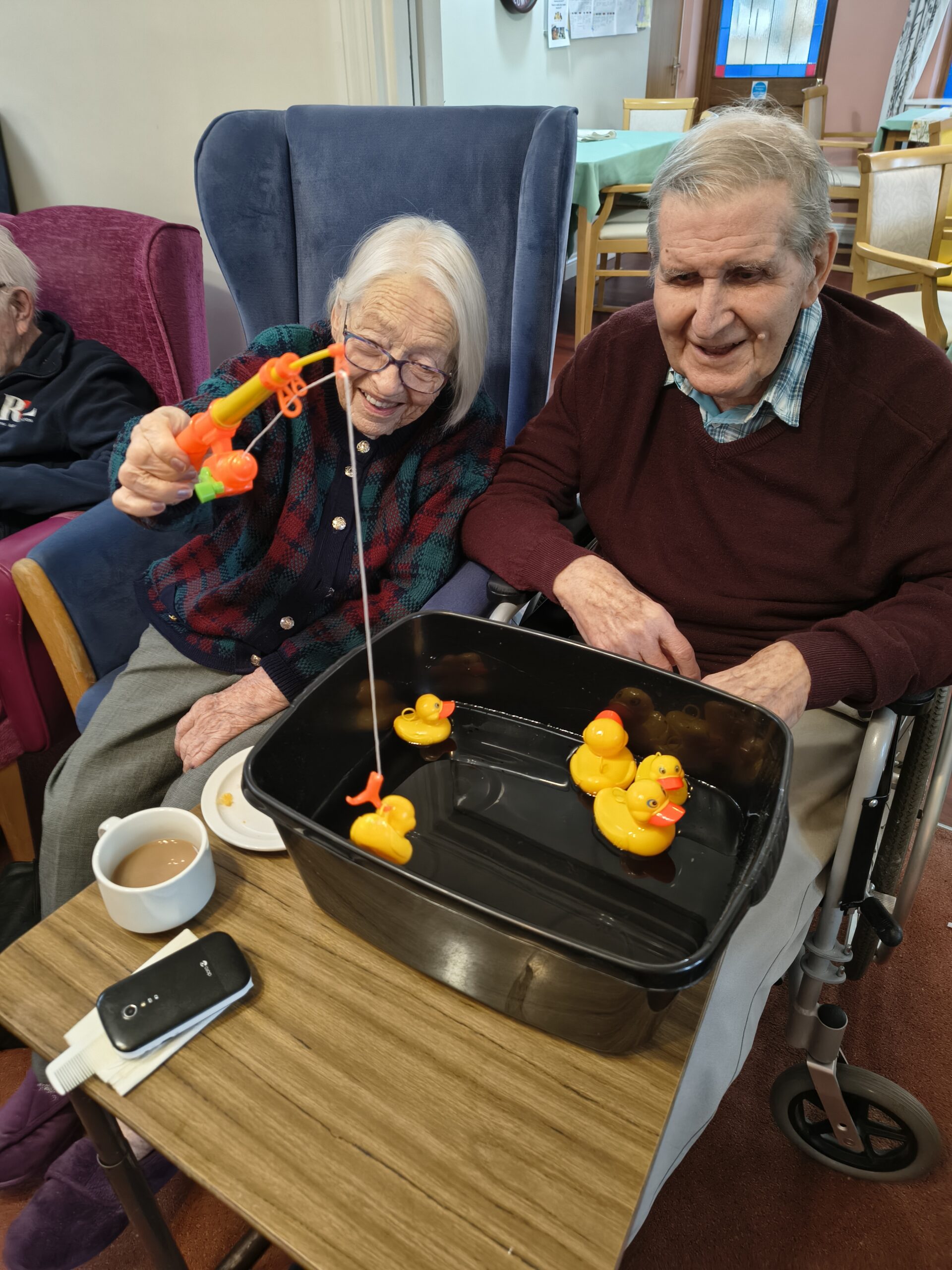 Female resident hooking a duck whilst another resident looks on scaled