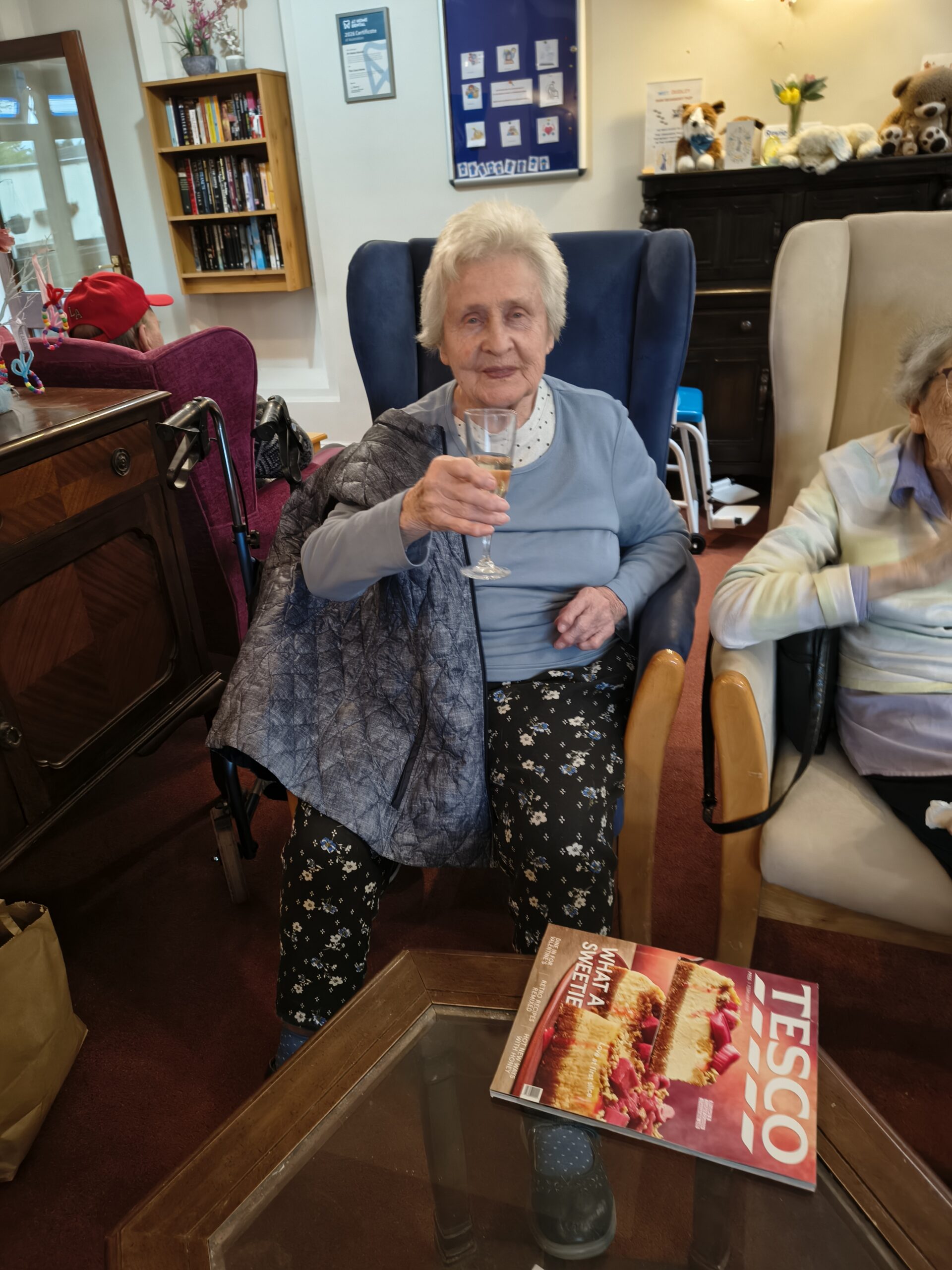 Female resident seated holding up a glass of bubbly smiling Female resident seated holding up a glass of bubbly smiling scaled
