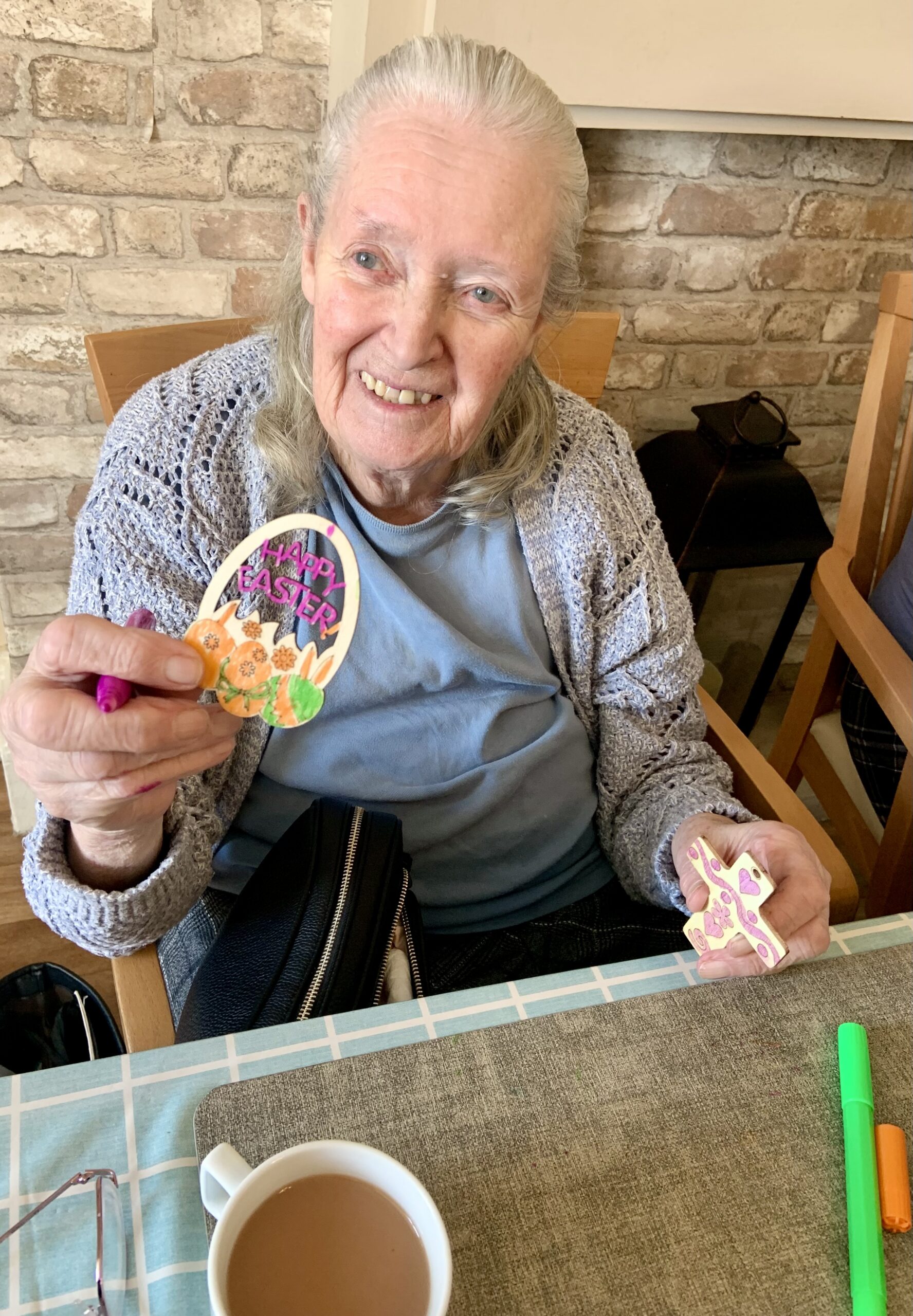 Female resident showing her finished paper Easter egg with a cup of tea scaled