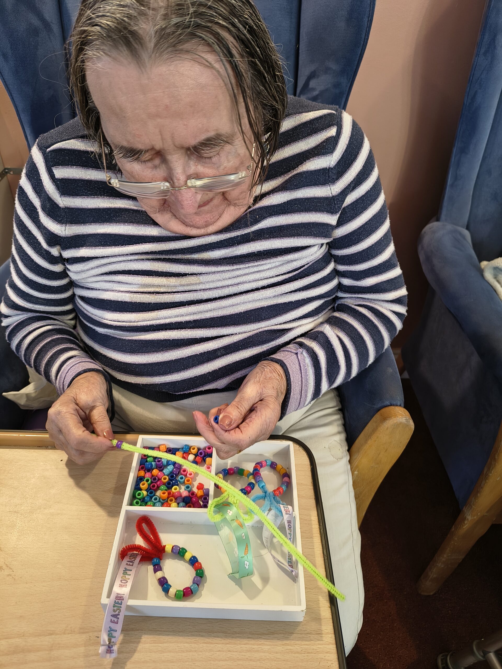 Female resident threading beads onto a pipe cleaner 1 scaled