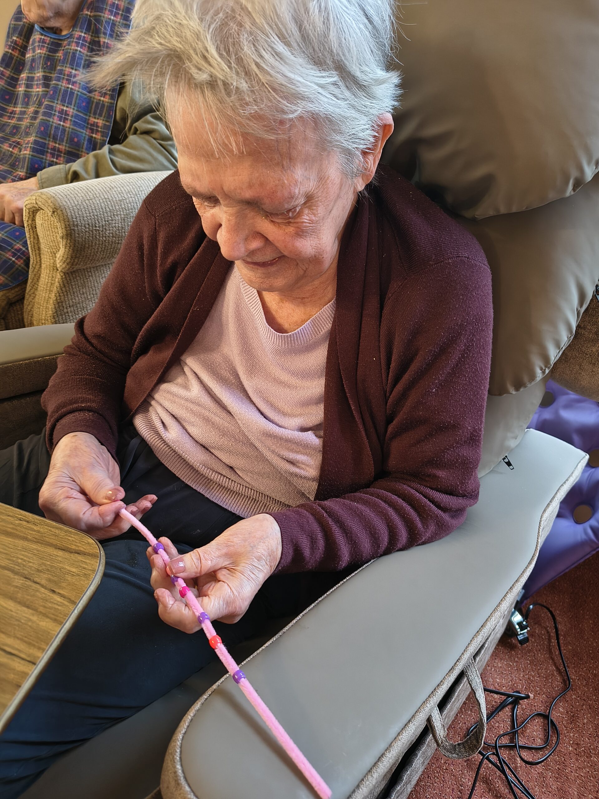 Female resident threading beads onto a pipe cleaner 2 scaled