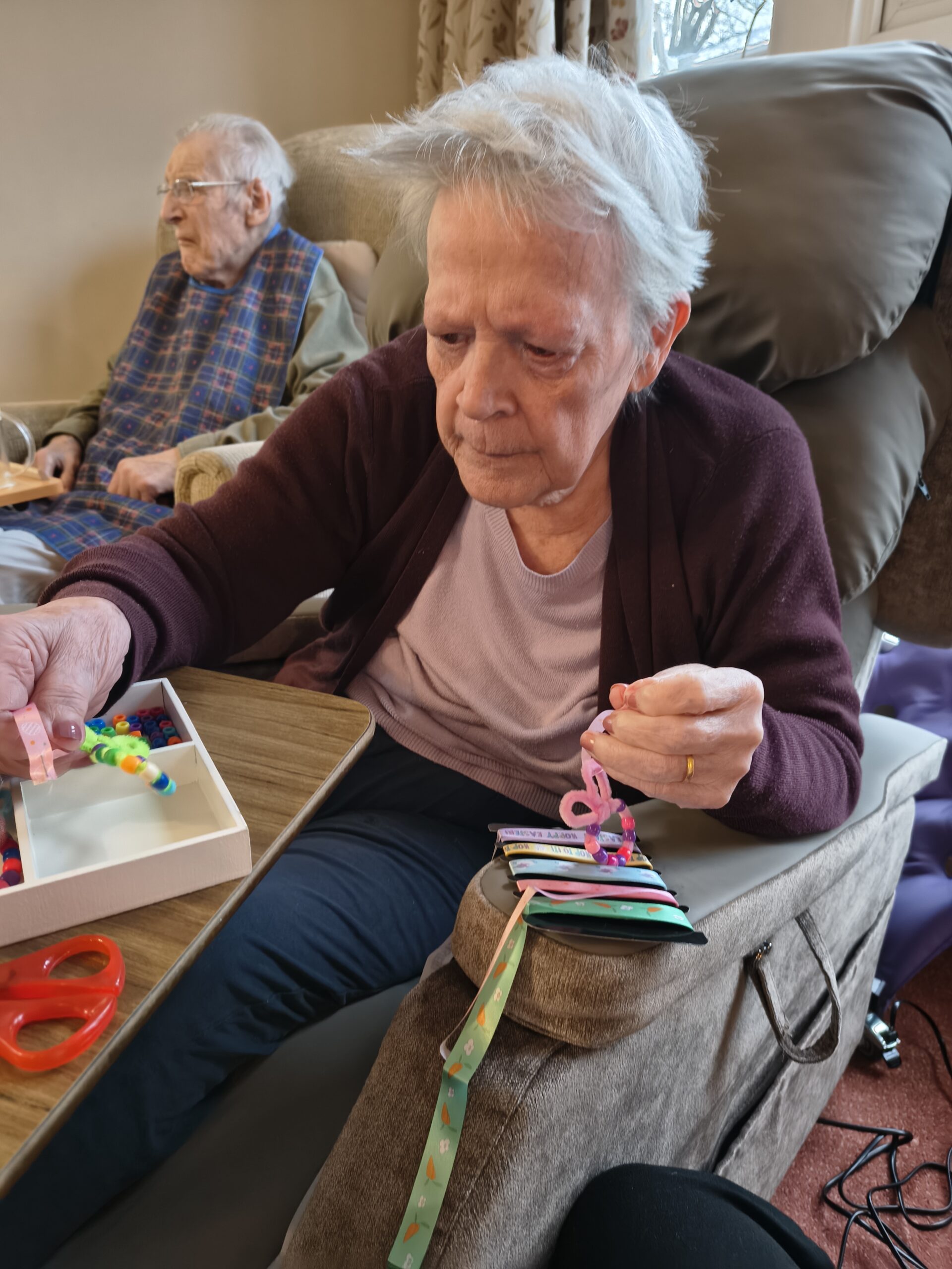 Female resident threading beads onto a pipe cleaner 3 scaled