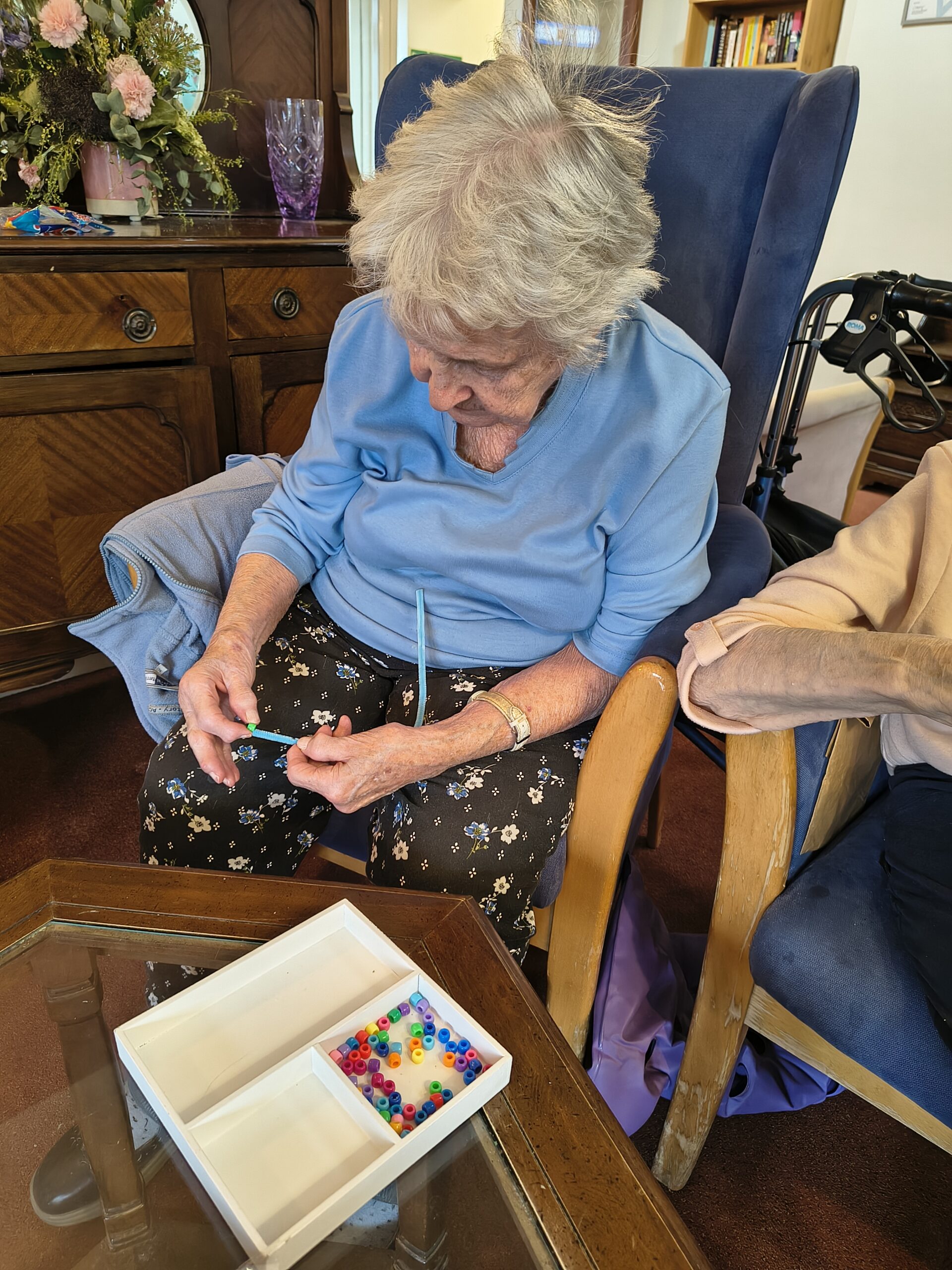 Female resident threading beads onto a pipe cleaner 6 scaled