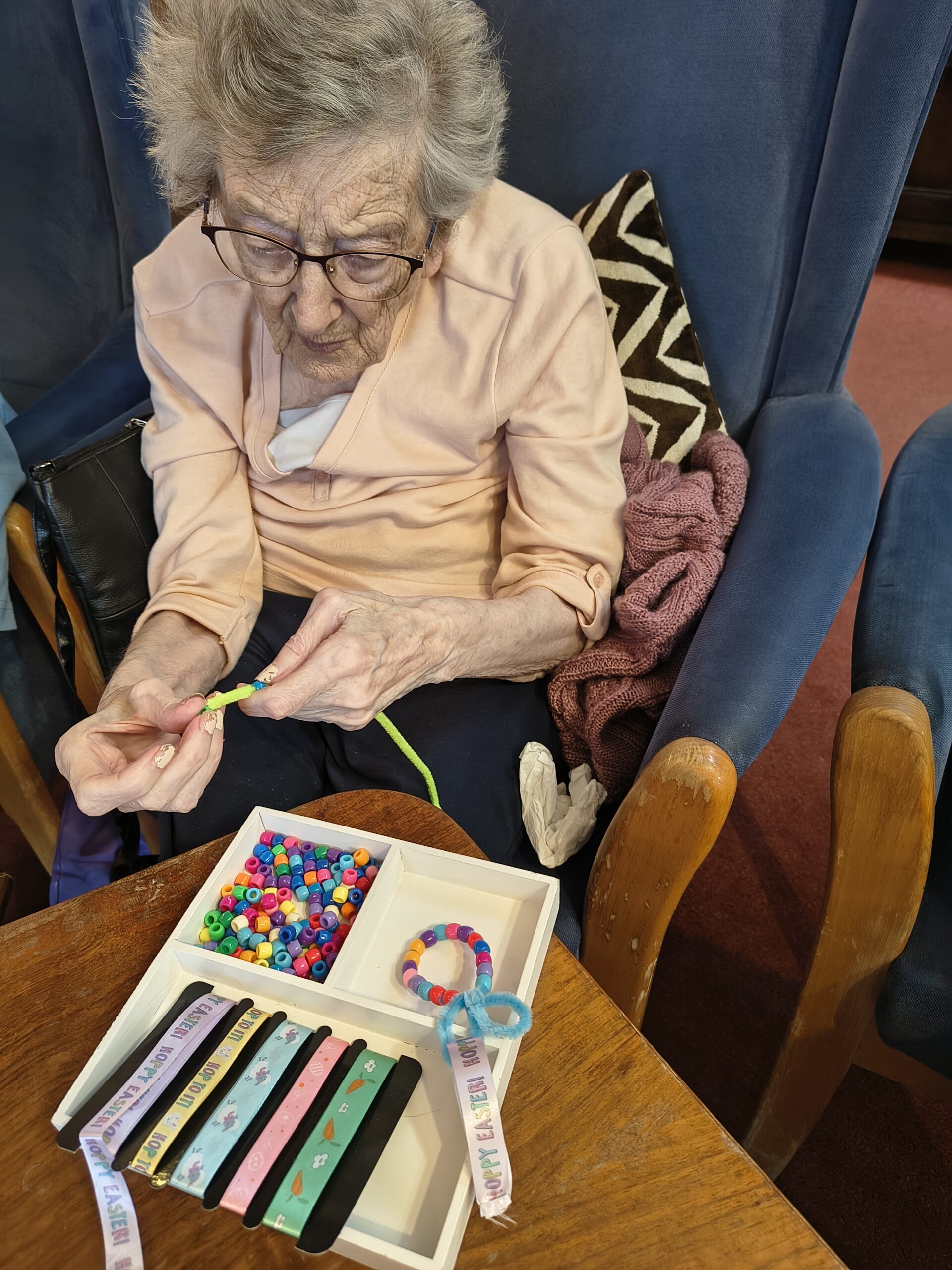 Female resident threading beads onto a pipe cleaner 7 scaled