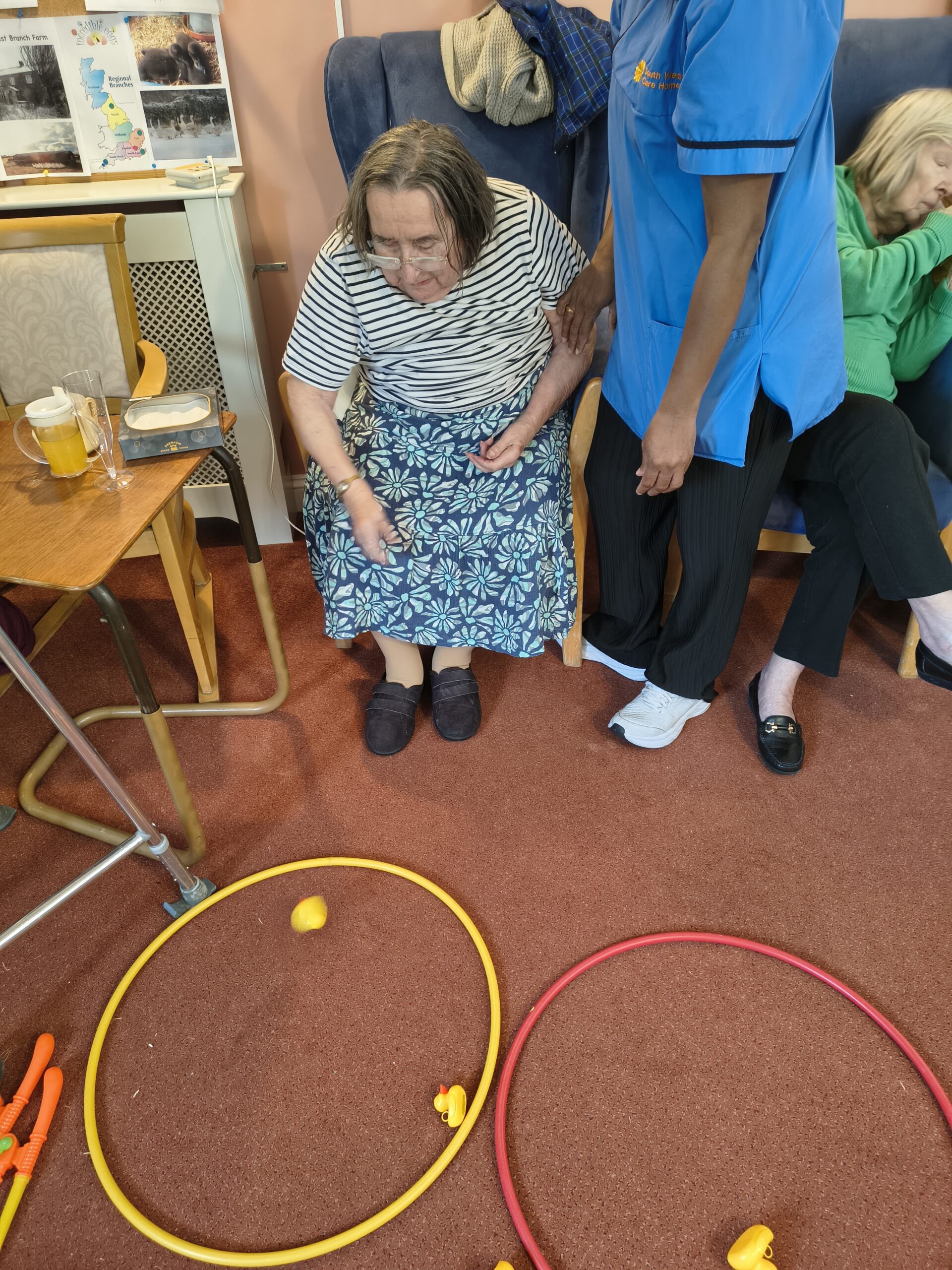 Female resident throwing a duck into a hoop on the ground with carer Female resident throwing a duck into a hoop on the ground with carer scaled