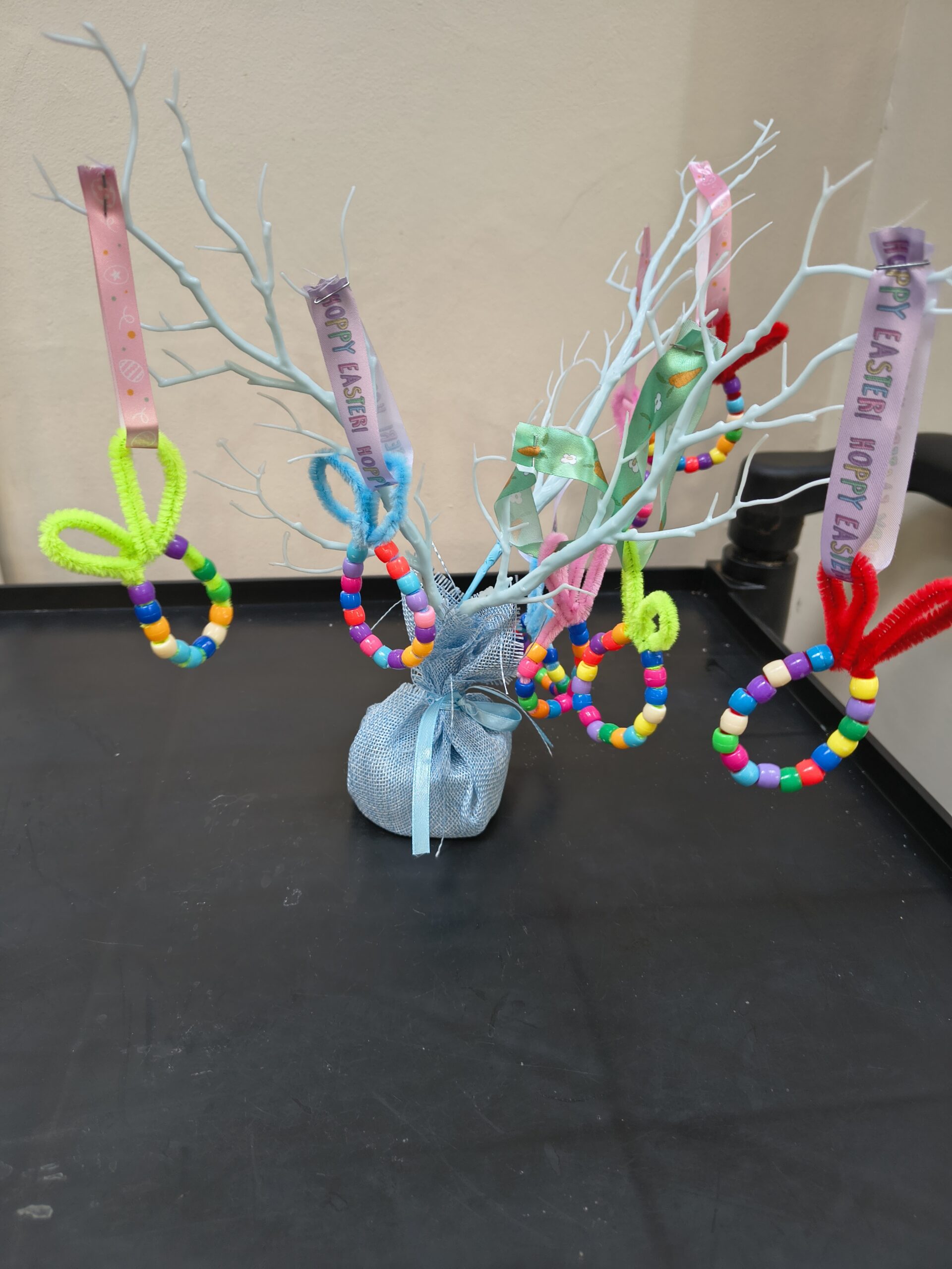 Finished beaded Easter eggs on display hanging on a small white twig tree scaled