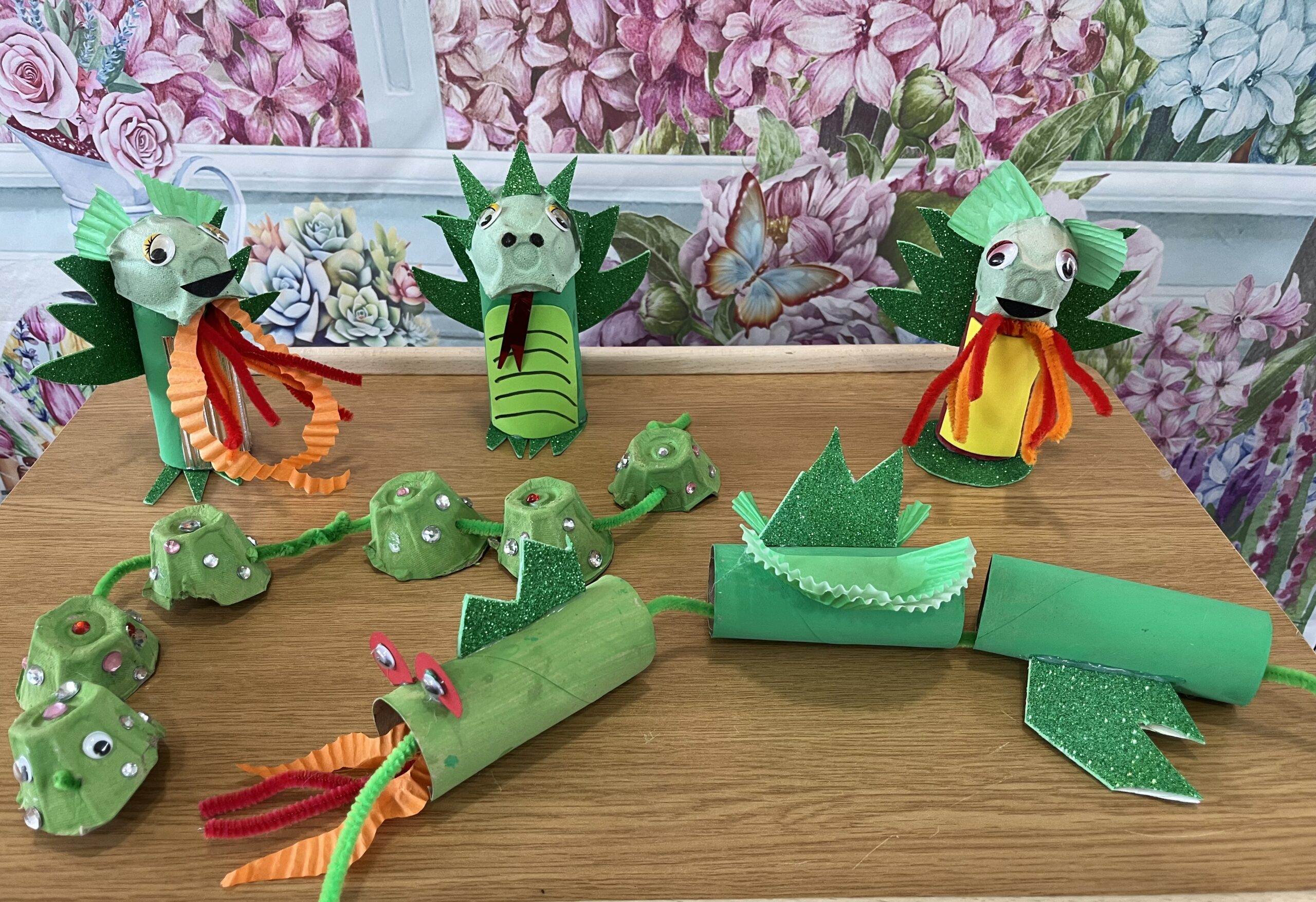 Finished dragons all made of toilet rolls egg boxes and decorated with pipe cleaner paper and sequins scaled