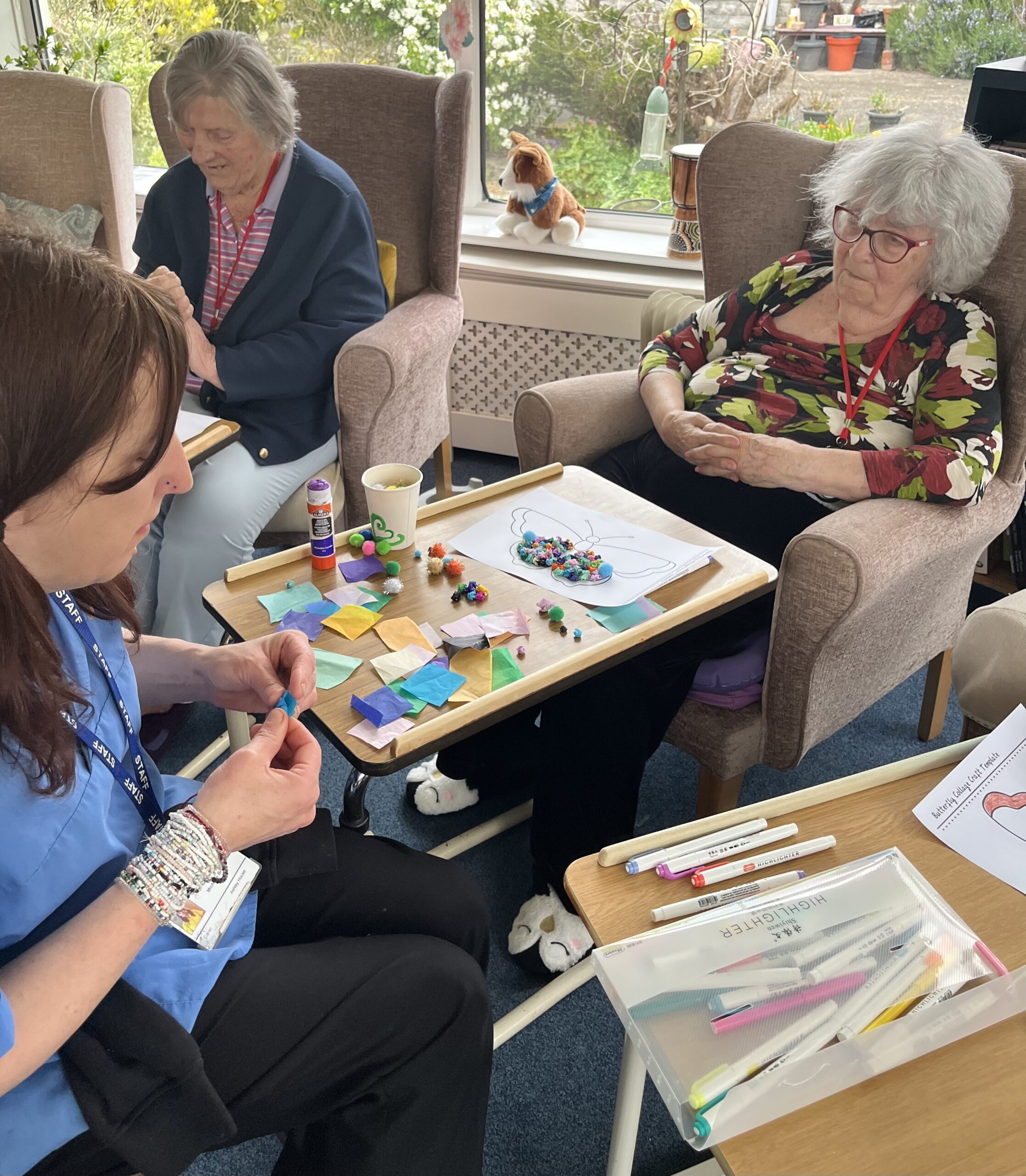 Maggie and a carer working together making tissue paper balls to stick on her butterfly scaled