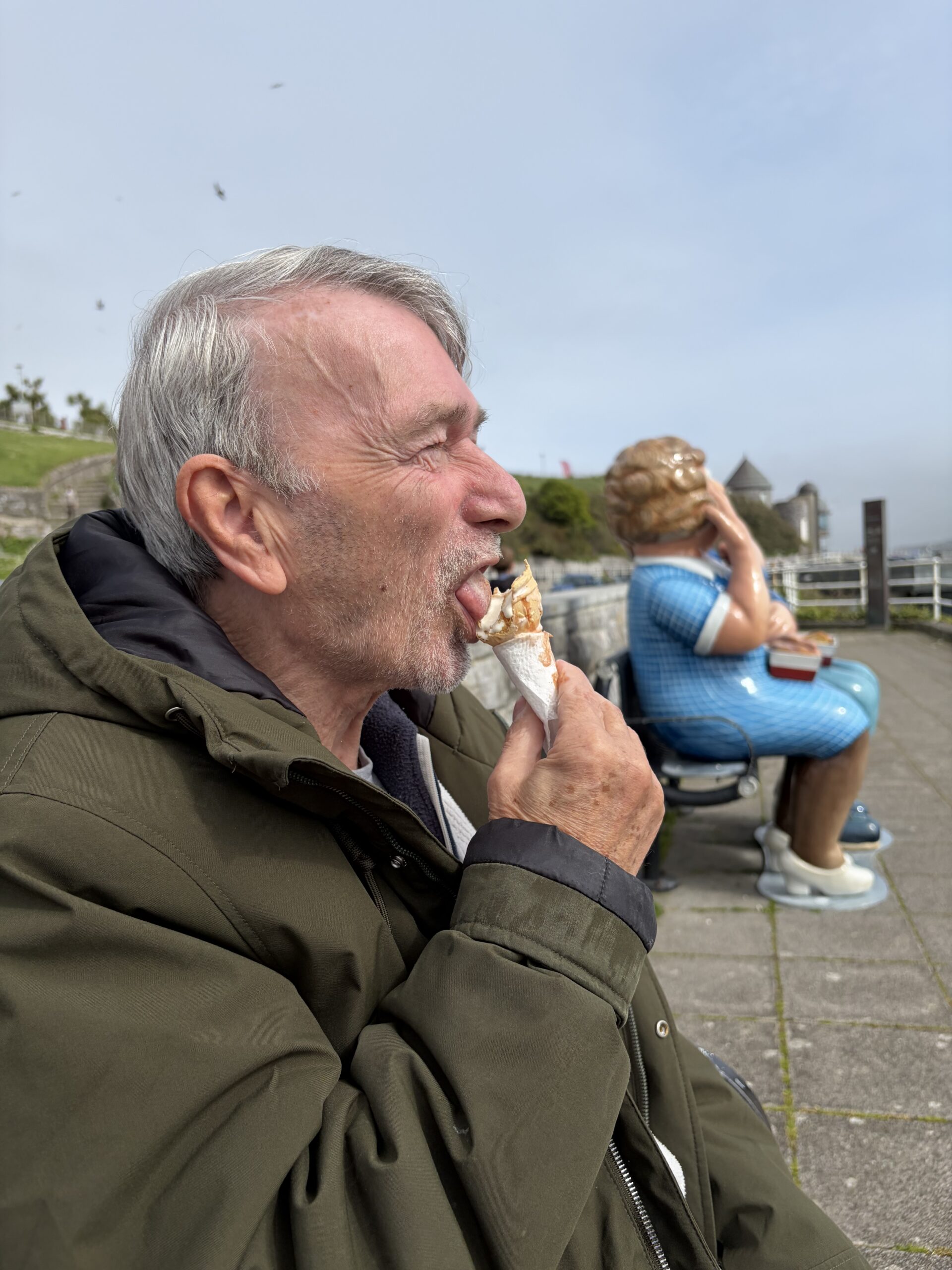 Martin eating his ice cream on a bench looking out to sea scaled