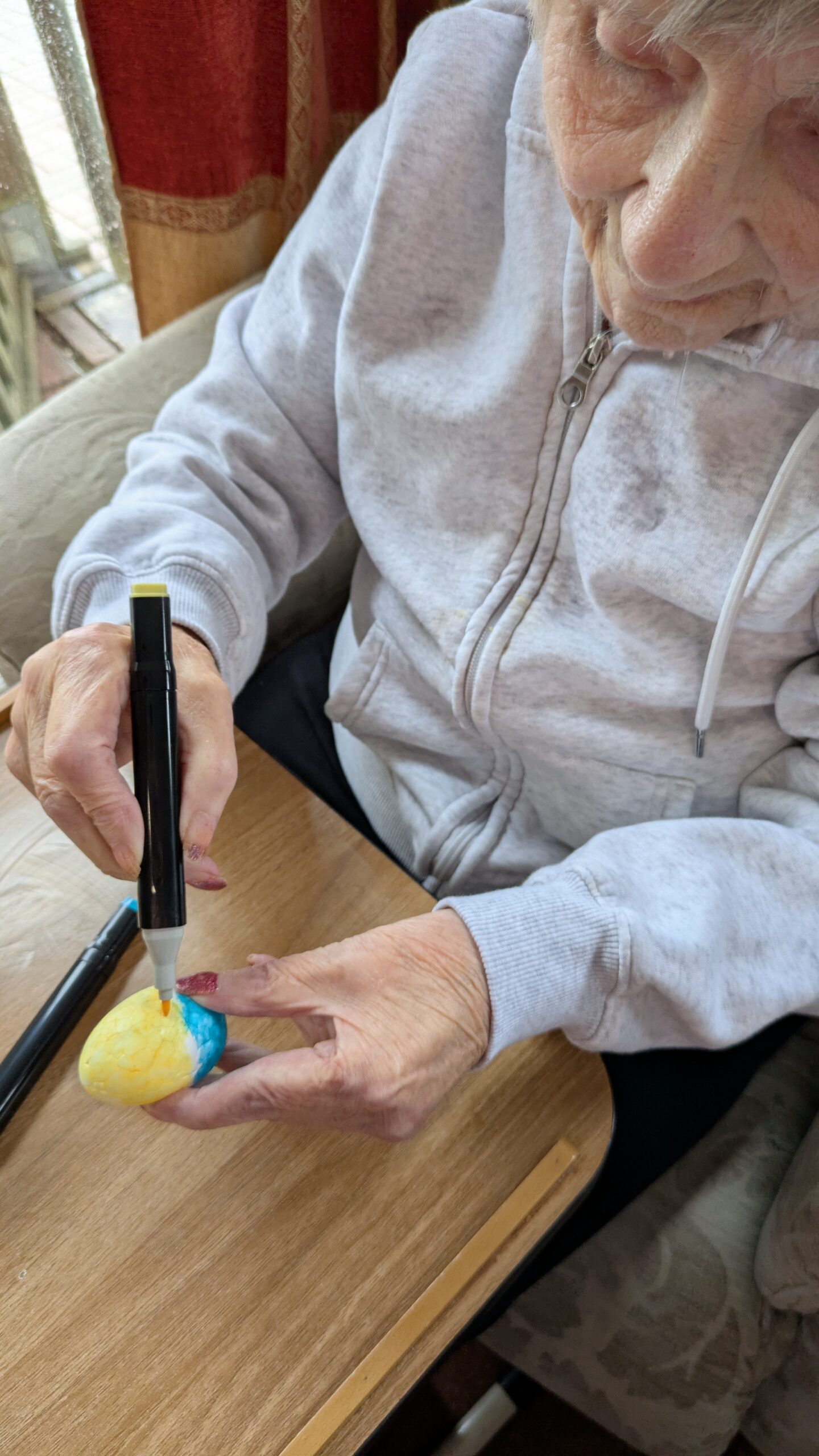 Mo decorating her foam Easter egg with yellow and blue felt tip pen scaled
