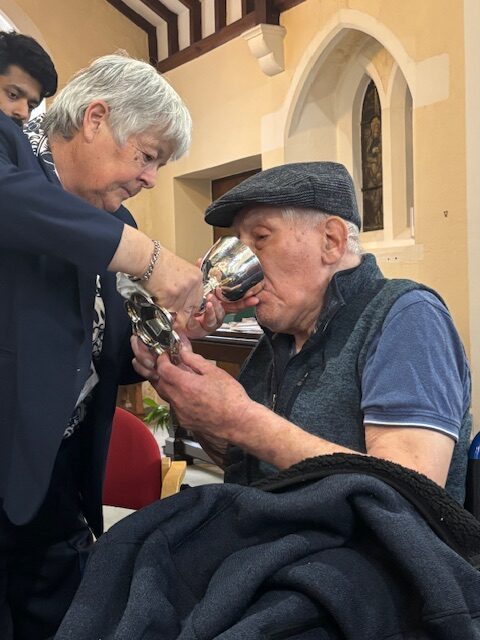 Pastor Kim giving Holy Communion to a male resident rotated