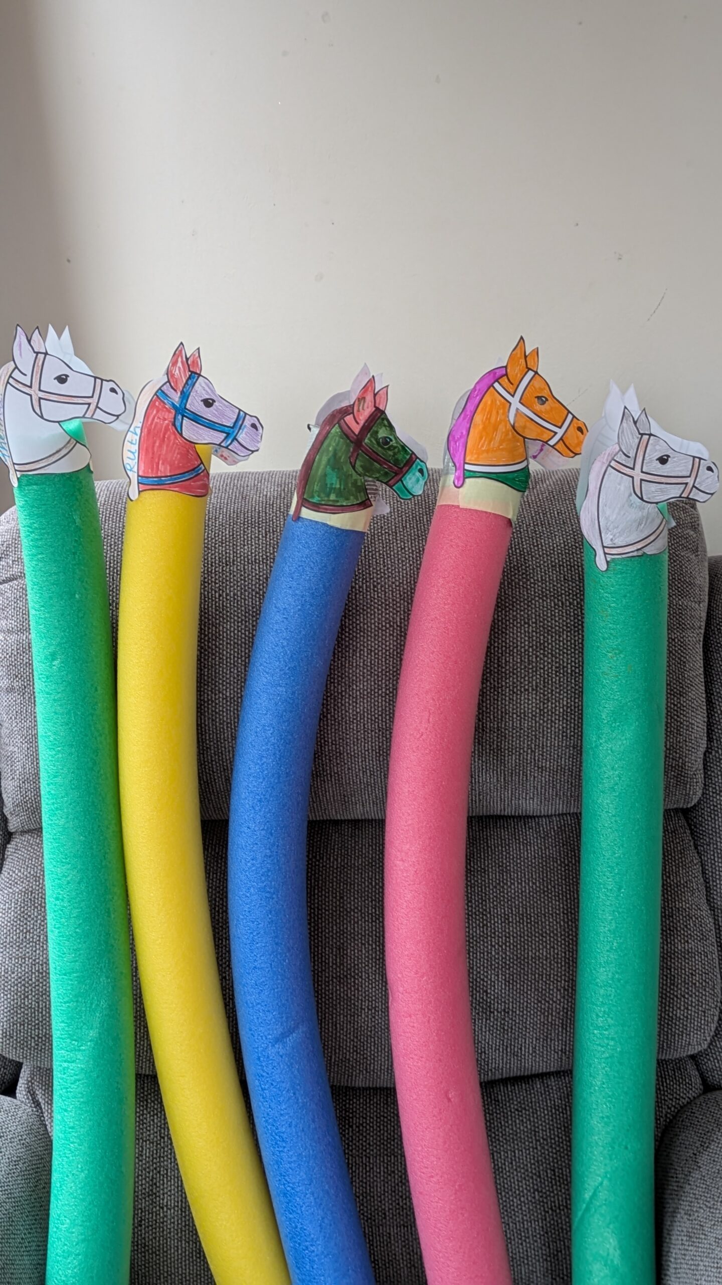 Pool noodles with paper race horse heads scaled