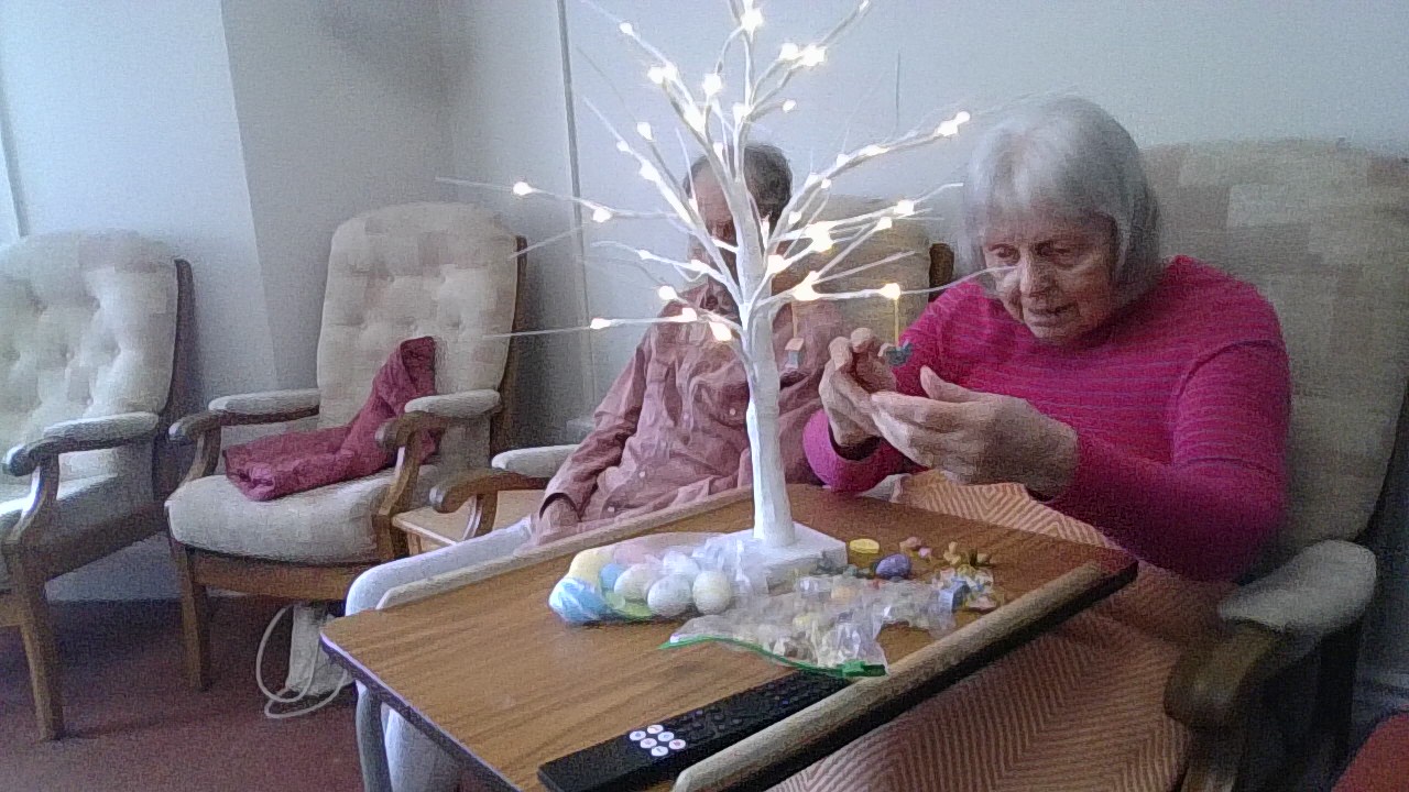 Resident decorating a decorative white tree stand with Easter decorations