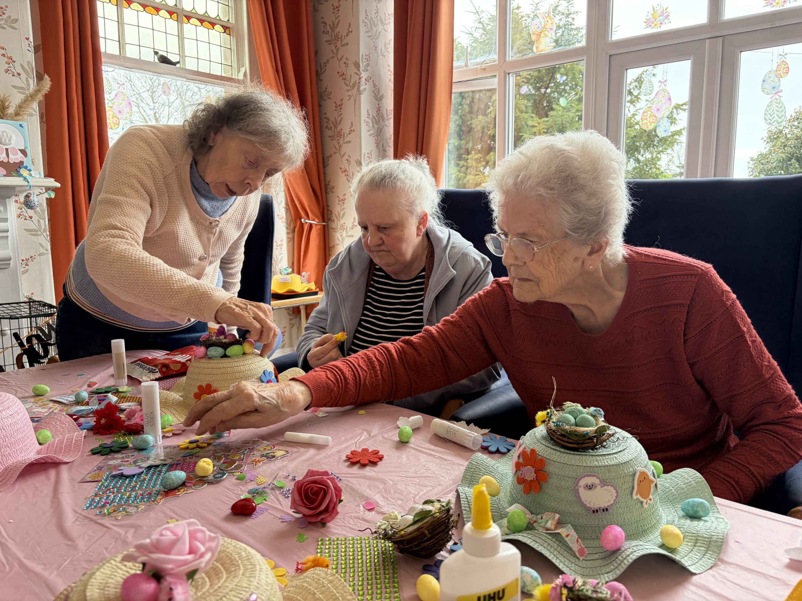 Residents seated around a table decorating Easter bonnets scaled