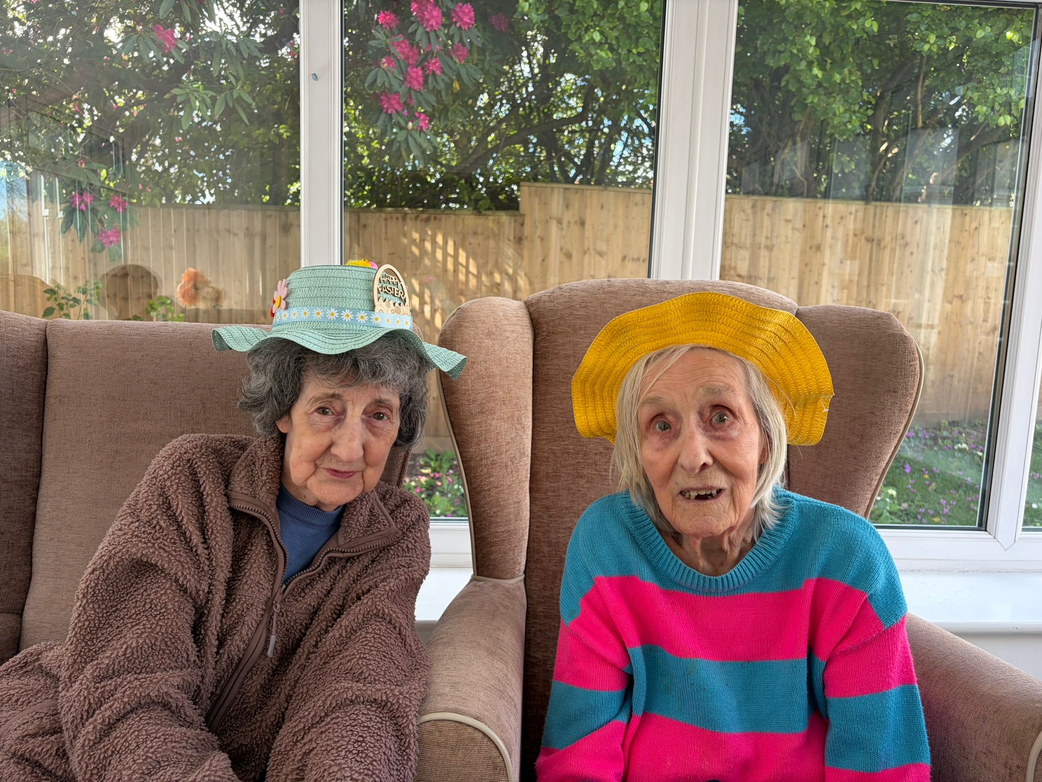 Residents seated in the conservatory wearing Easter bonnets