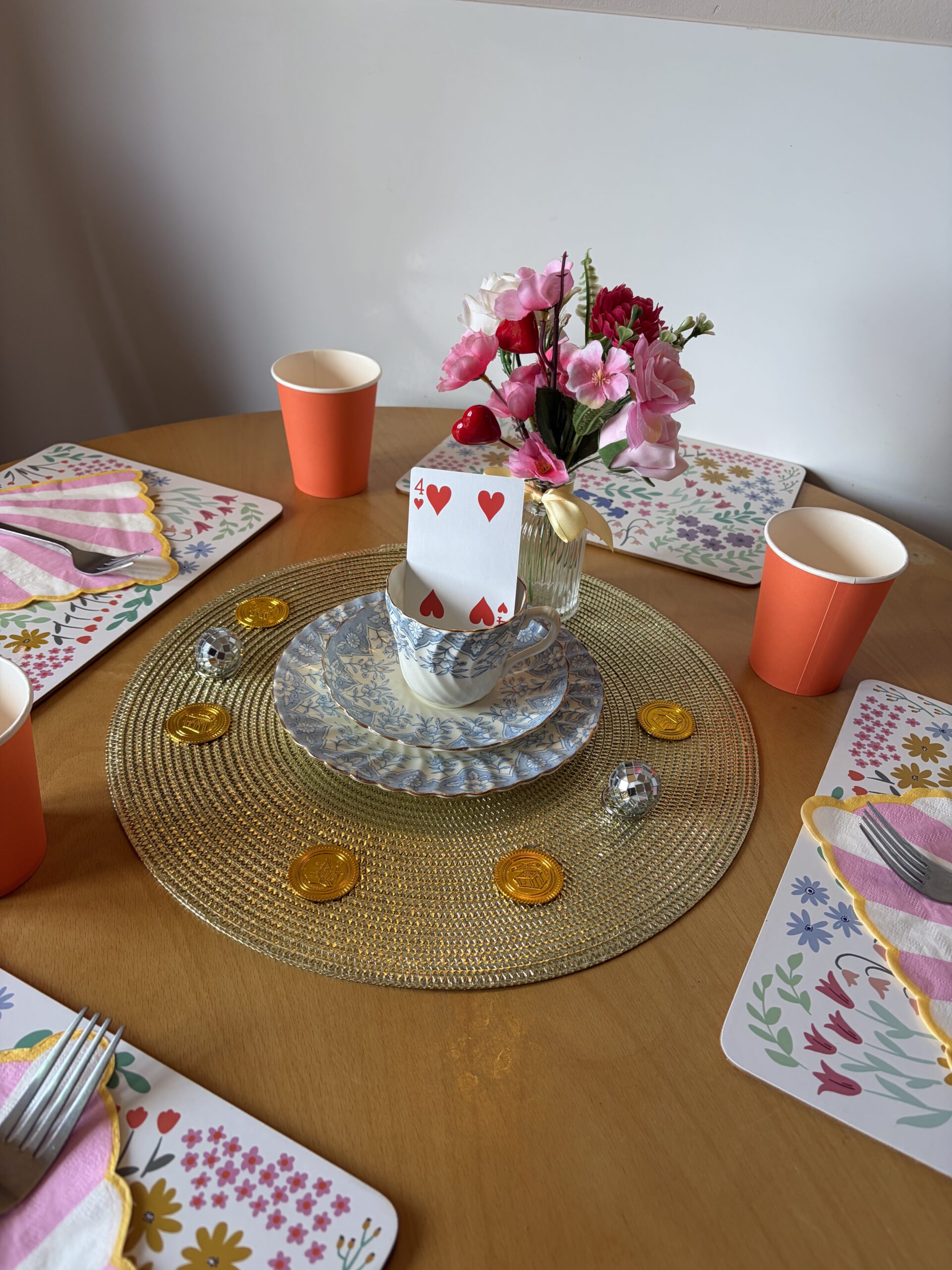 Table decoration of teacup and saucers with a playing card gold coins and mini disco balls scaled