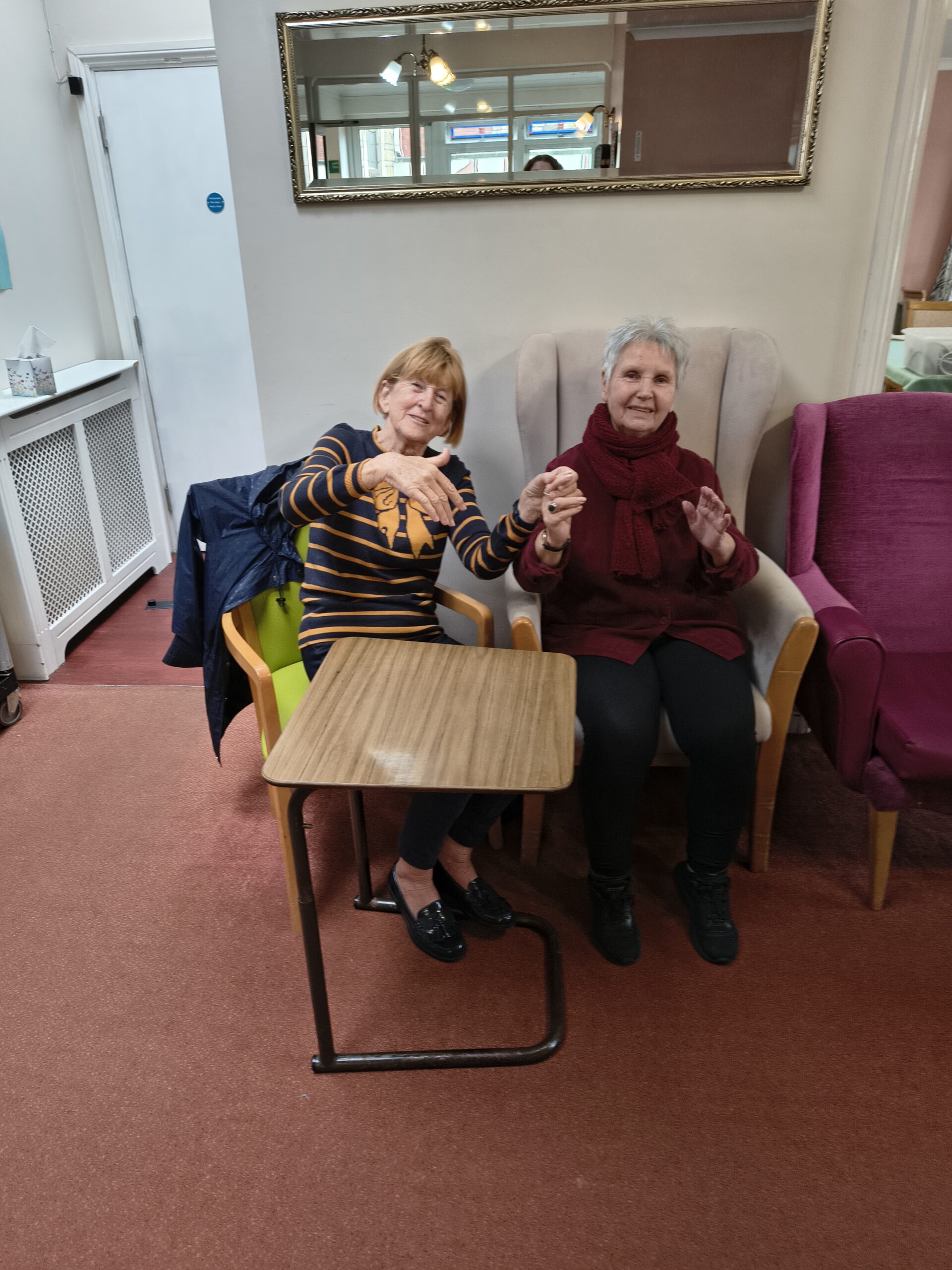 Two female residents holding hands swinging to the music scaled