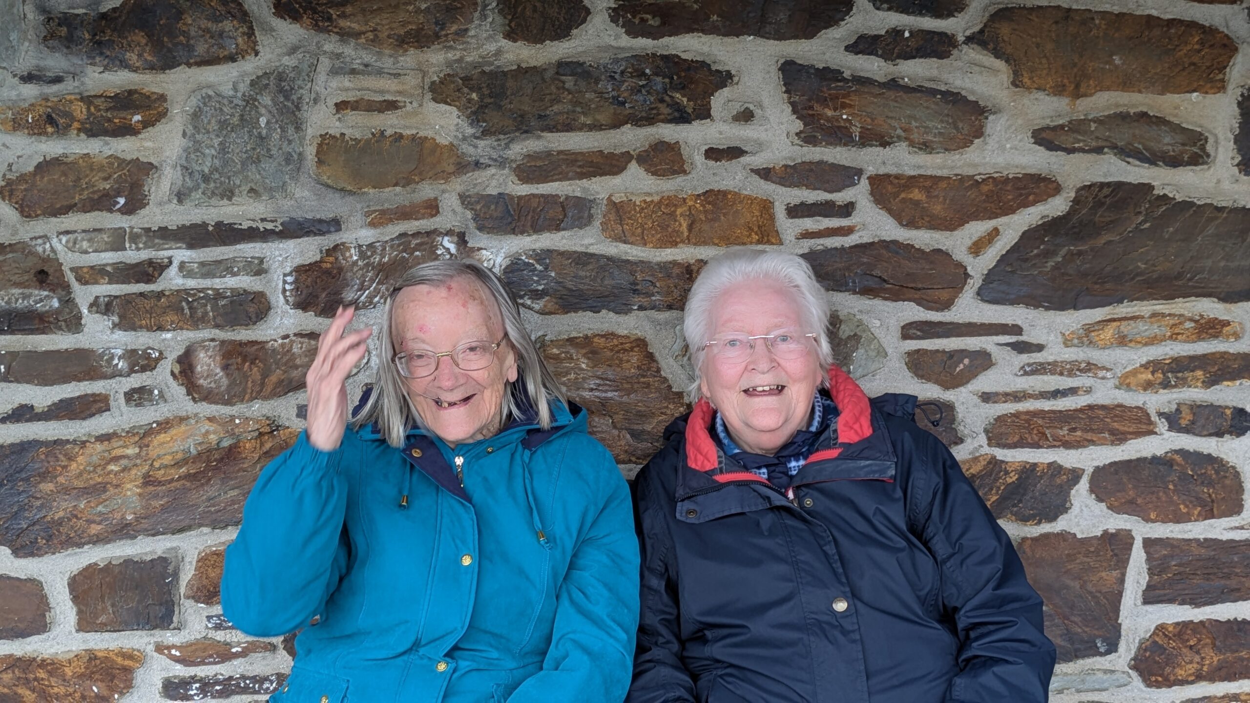 Two female residents wrapped up in warm coats sitting outside and chatting scaled