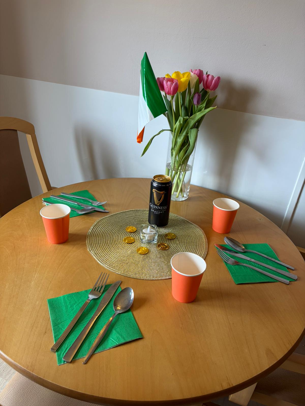 A table decorated with green napkins orange cups and a can of Guinness