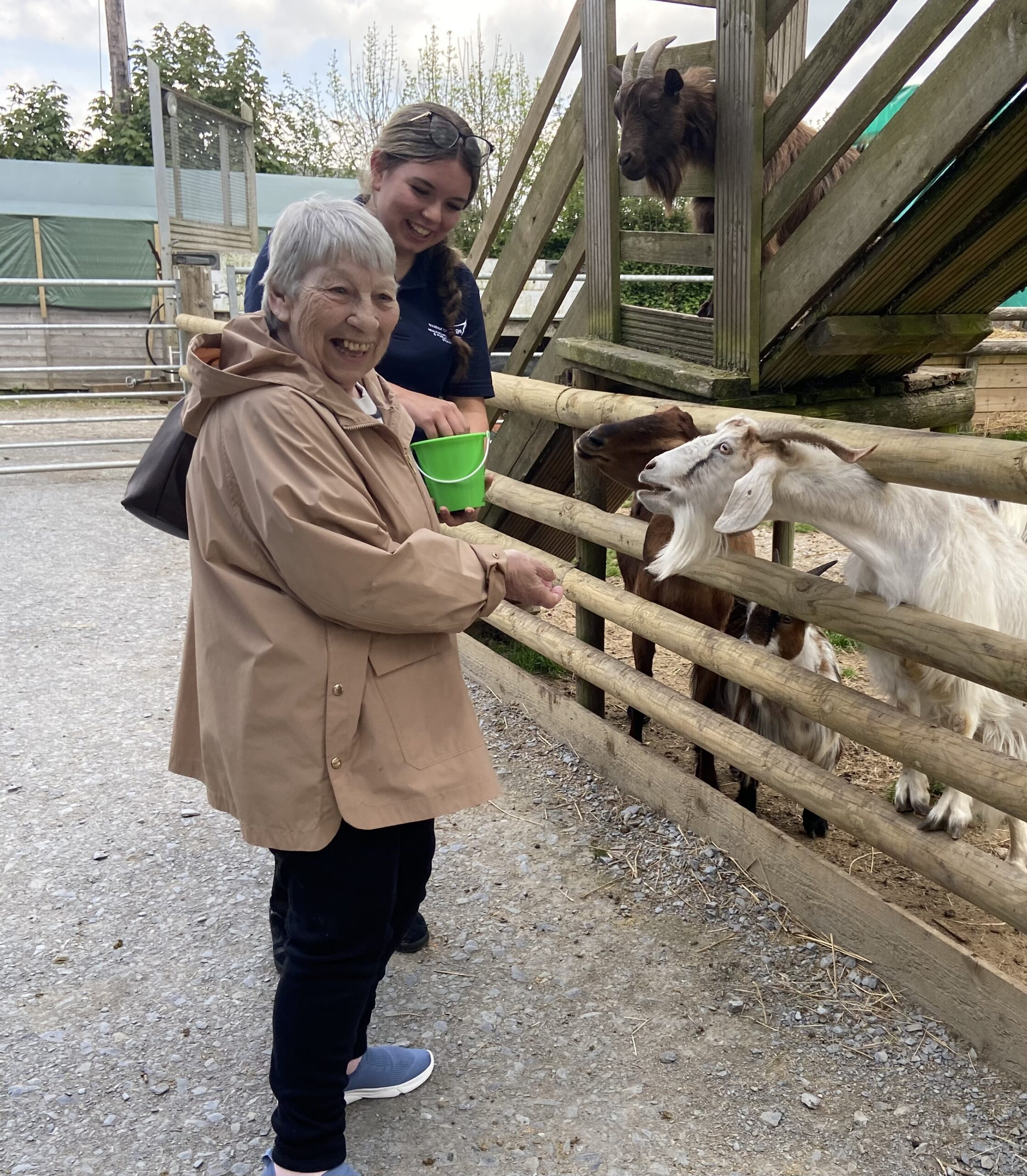 Amber and Ange both smiling feeding the goats scaled
