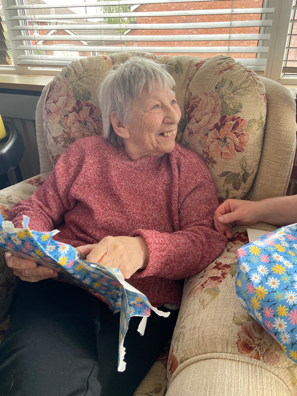 Ange smiling opening her presents and chatting to the carers