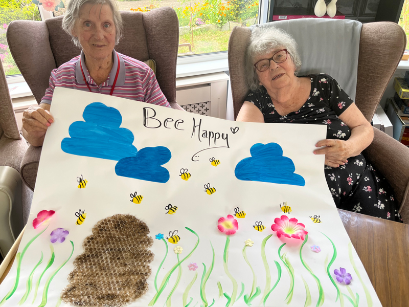 Barb and Maggie holding up finished Bee Happy poster