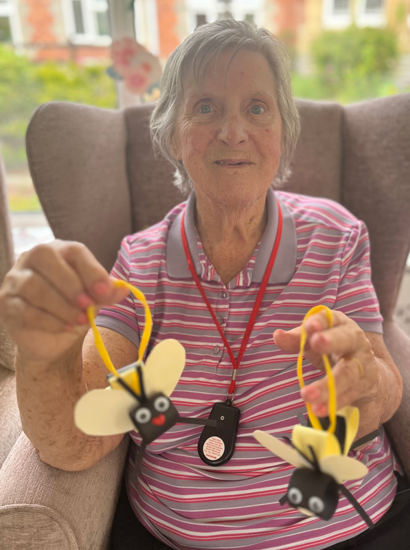 Barb holding up two finished bees made of card and pipe cleaners