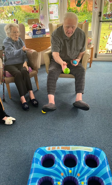 Bill seated throwing a ball at a 3x3 hole blow up mat
