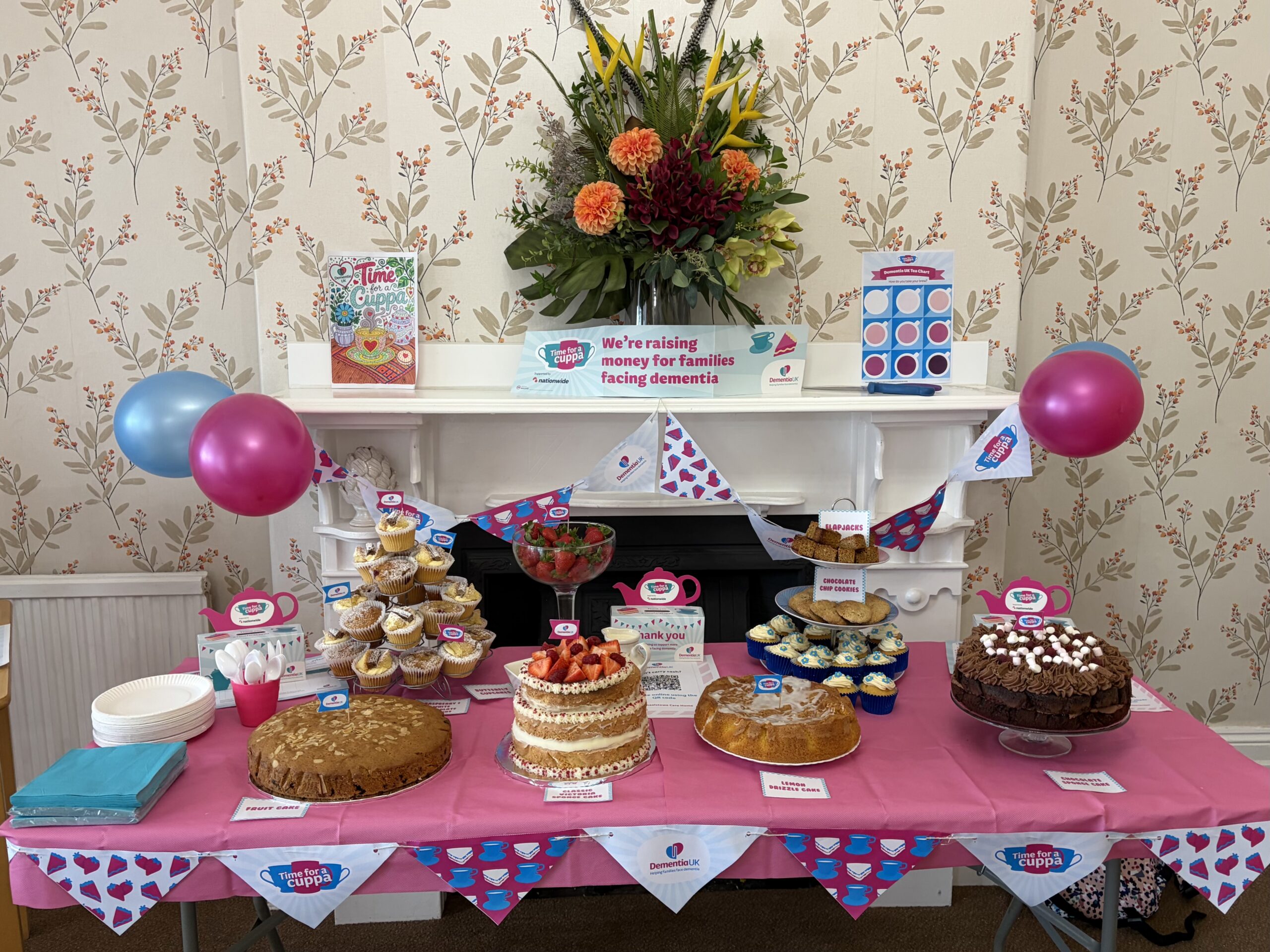 Cakes for the bake sale on a decorated table with bunting and balloons scaled