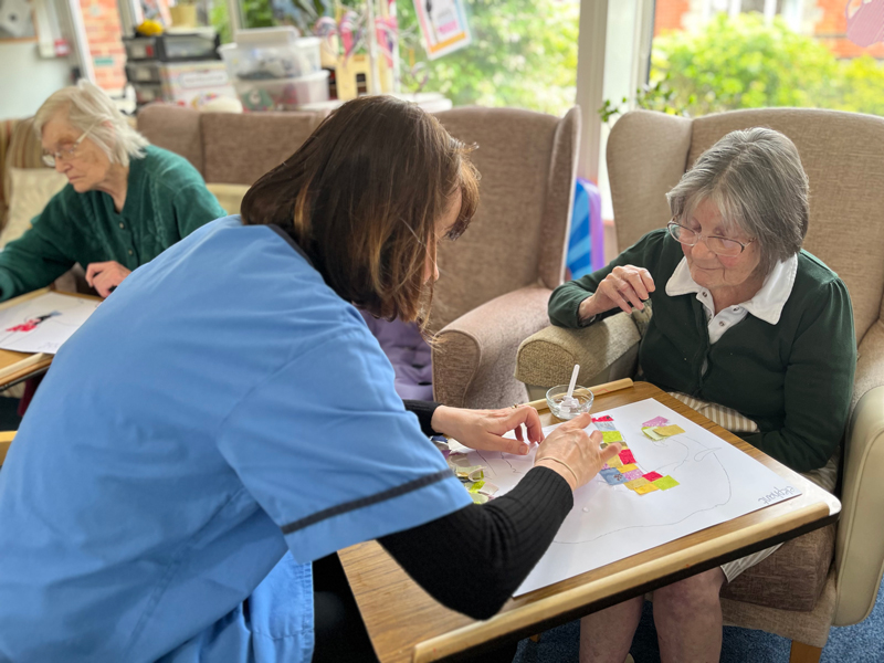 Carer Becky helping Eileen to glue on her squares