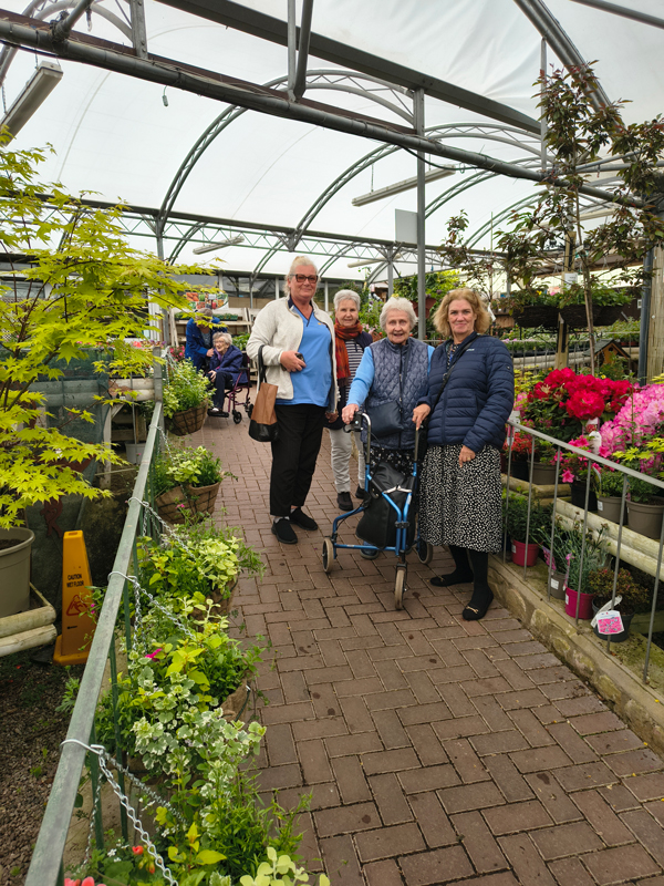 Carers and residents posing for a photo beside lots of plants