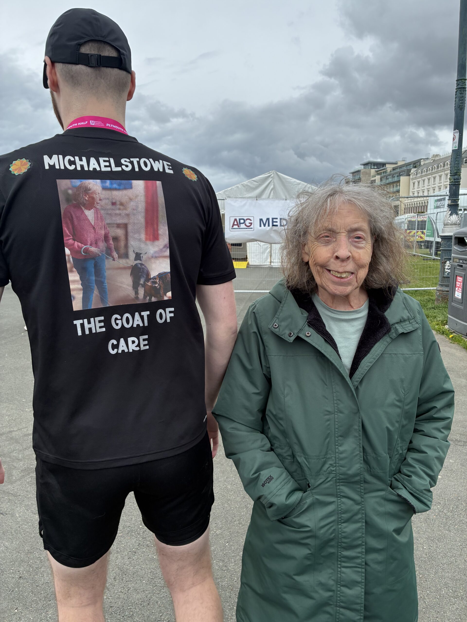 Carol stood beside Luke who is showing the back of his T shirt which says Michaelstowe The GOAT of care scaled