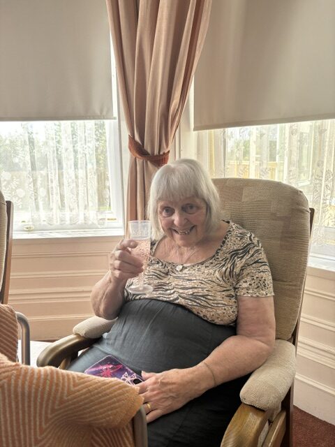 Cheers female resident raising her glass of bubbly rotated