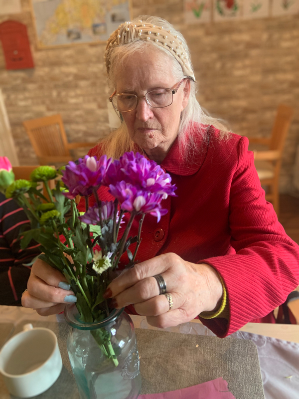 Female resident busy arranging flowers in a glass vase