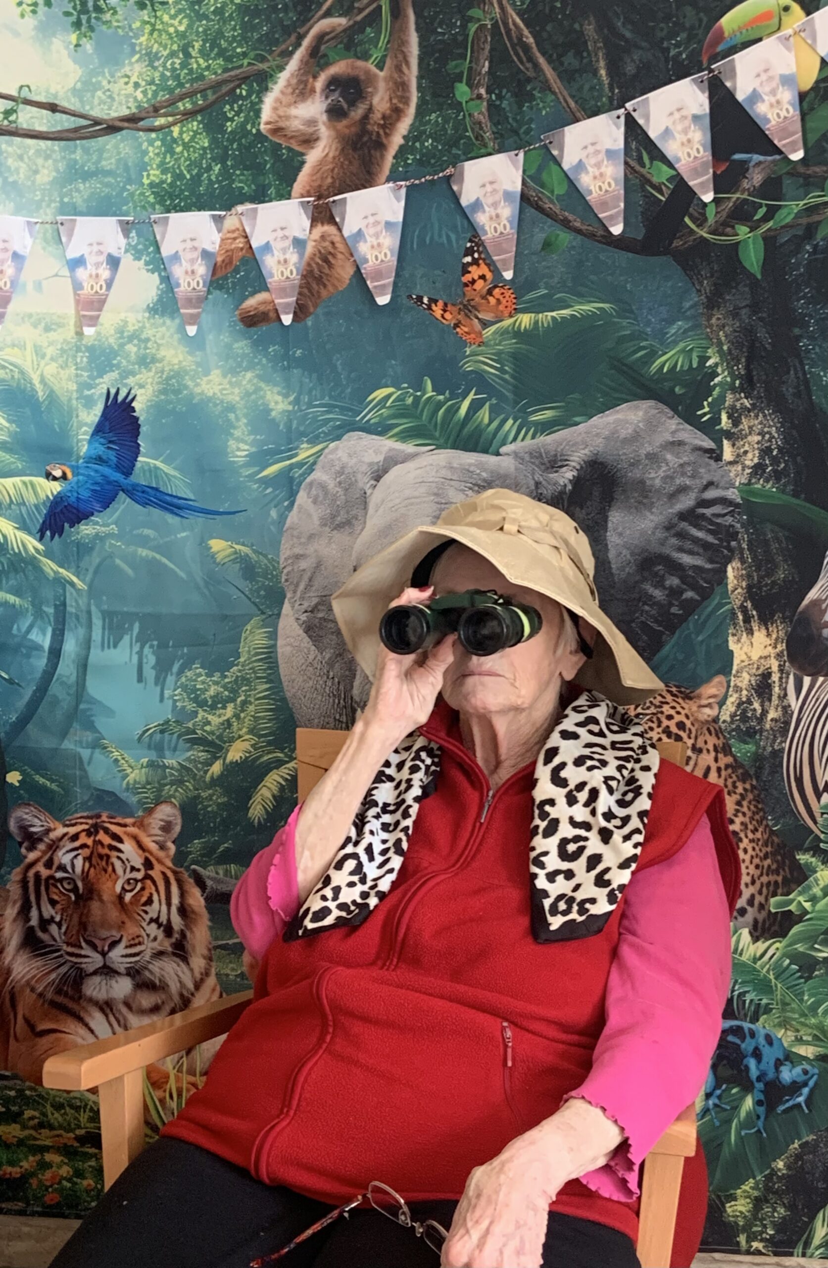 Female resident looking through binoculars seated in front of jungle back drop scaled