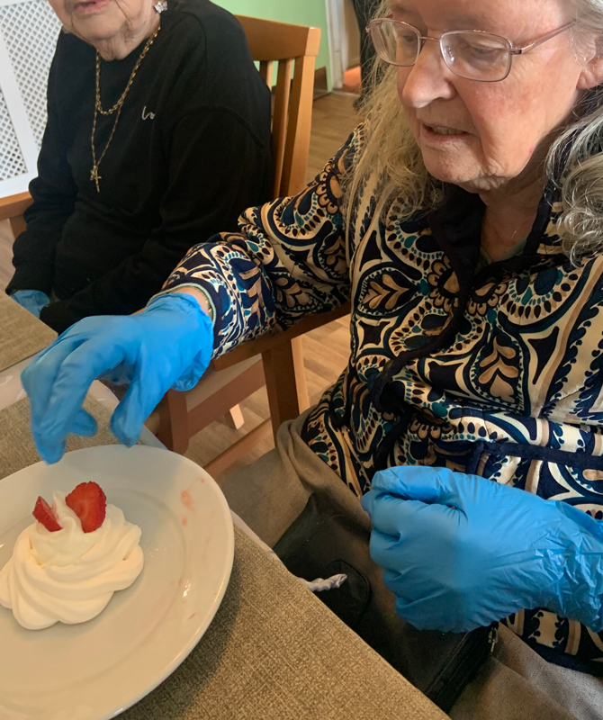 Female resident placing strawberries on top of a single pavlova