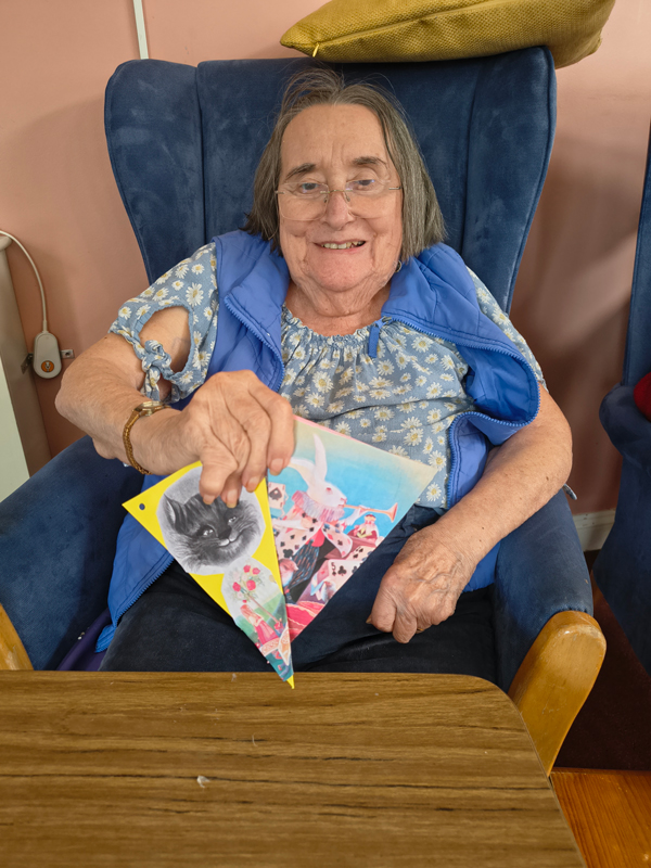 Female resident proudly showing her 2 finished pieces of decorated bunting