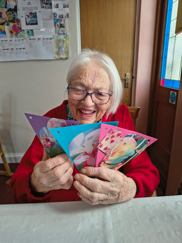 Female resident proudly showing her 3 finished pieces of bunting