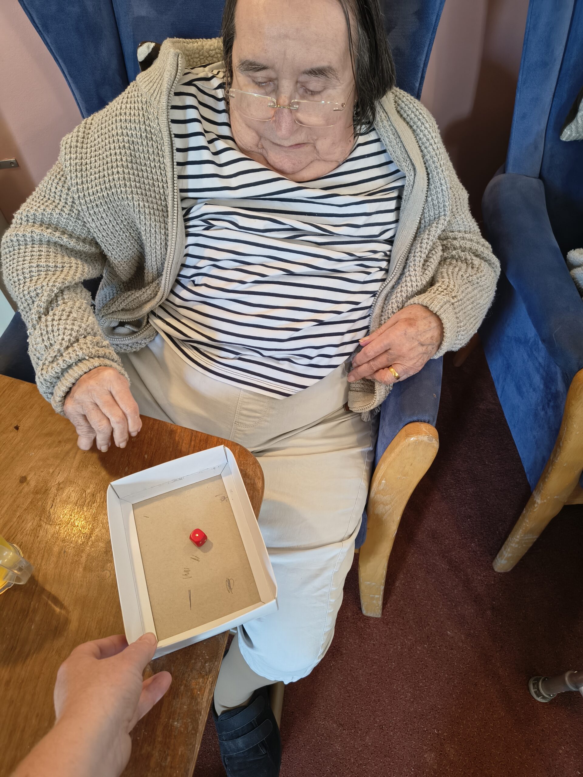 Female resident rolling a die in a box for the duck race scaled