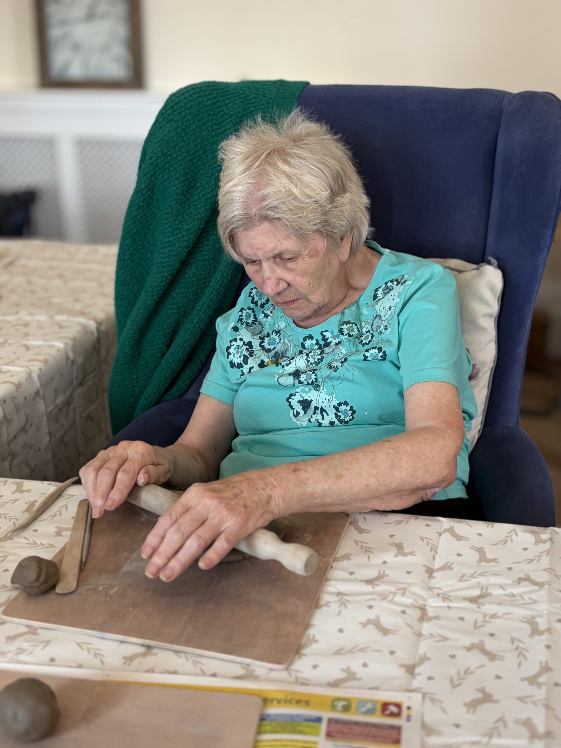 Female resident rolling a piece of clay with a rolling pin scaled