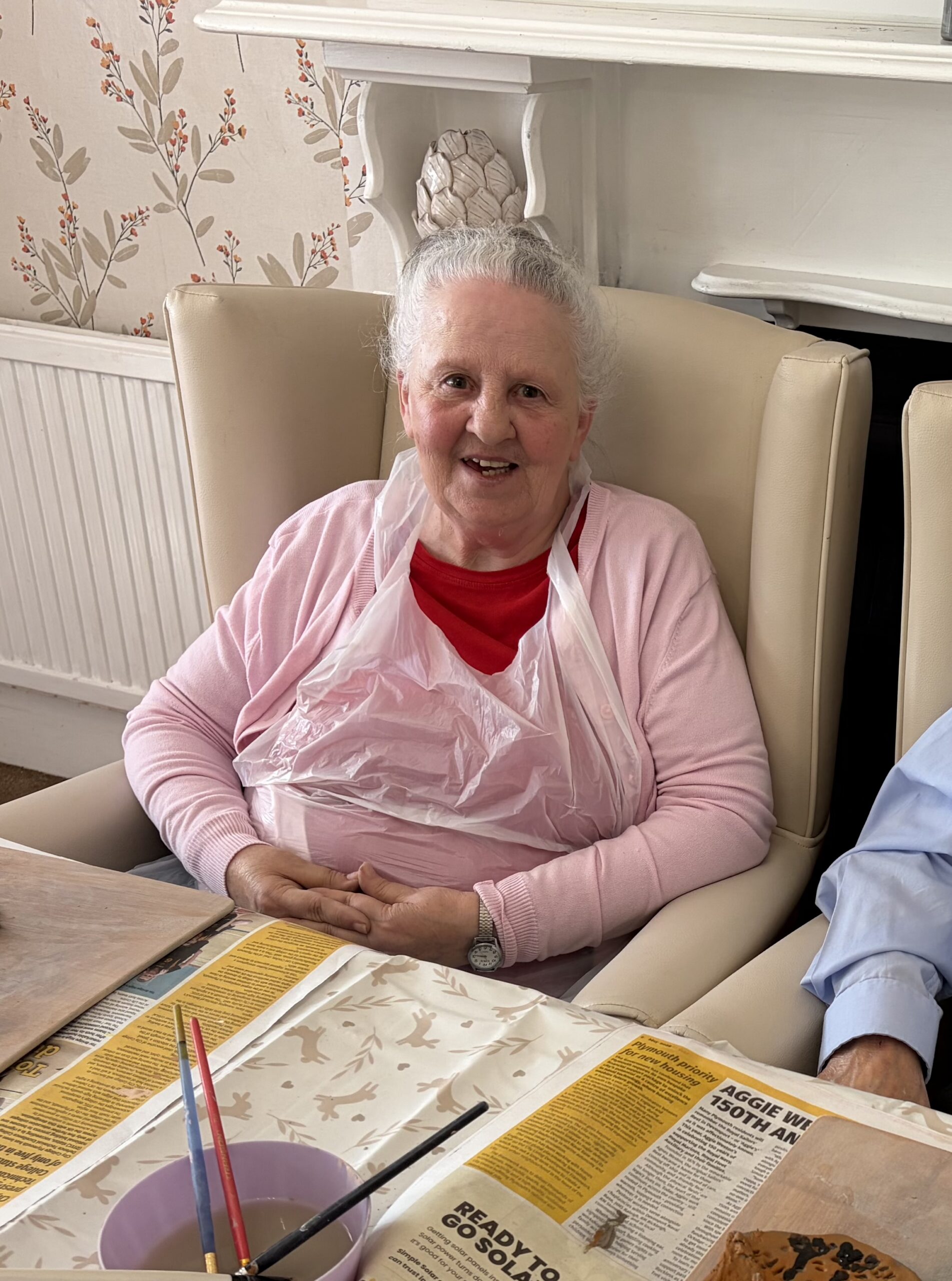 Female resident seated at the table smiling at the camera scaled